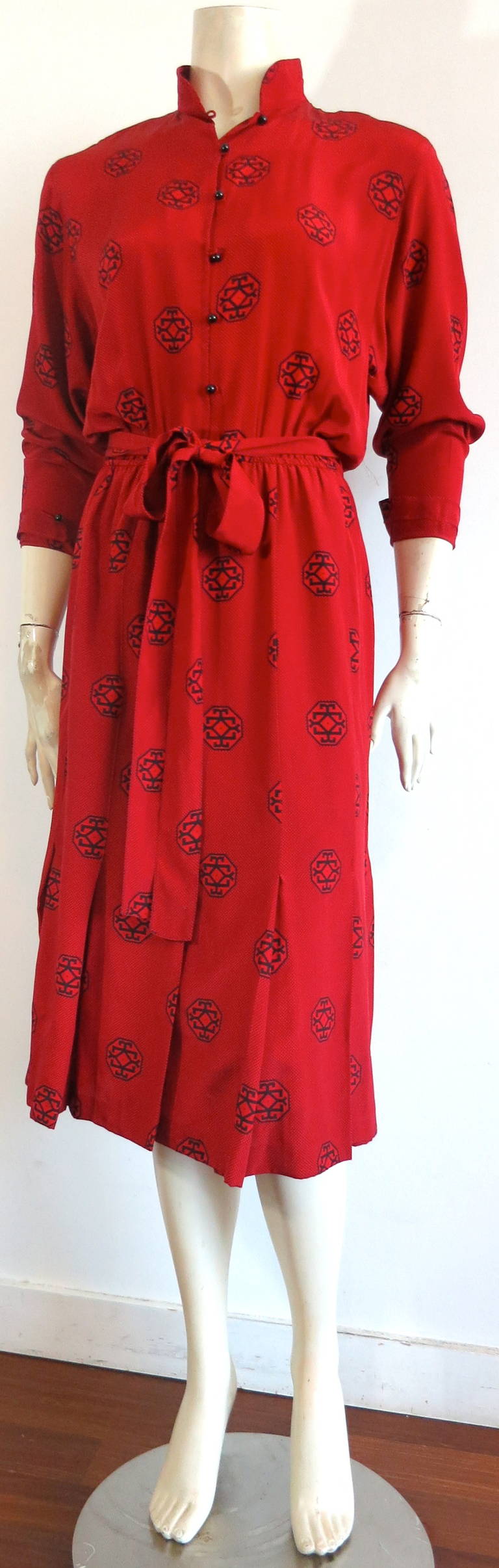 1970s GUY LAROCHE Red silk day dress.

The dress is in excellent condition, and features a mandarin collar style with black ball button closures at center-front and cuffs.

Stitched down pleated construction at bottom skirt hem.

Matching