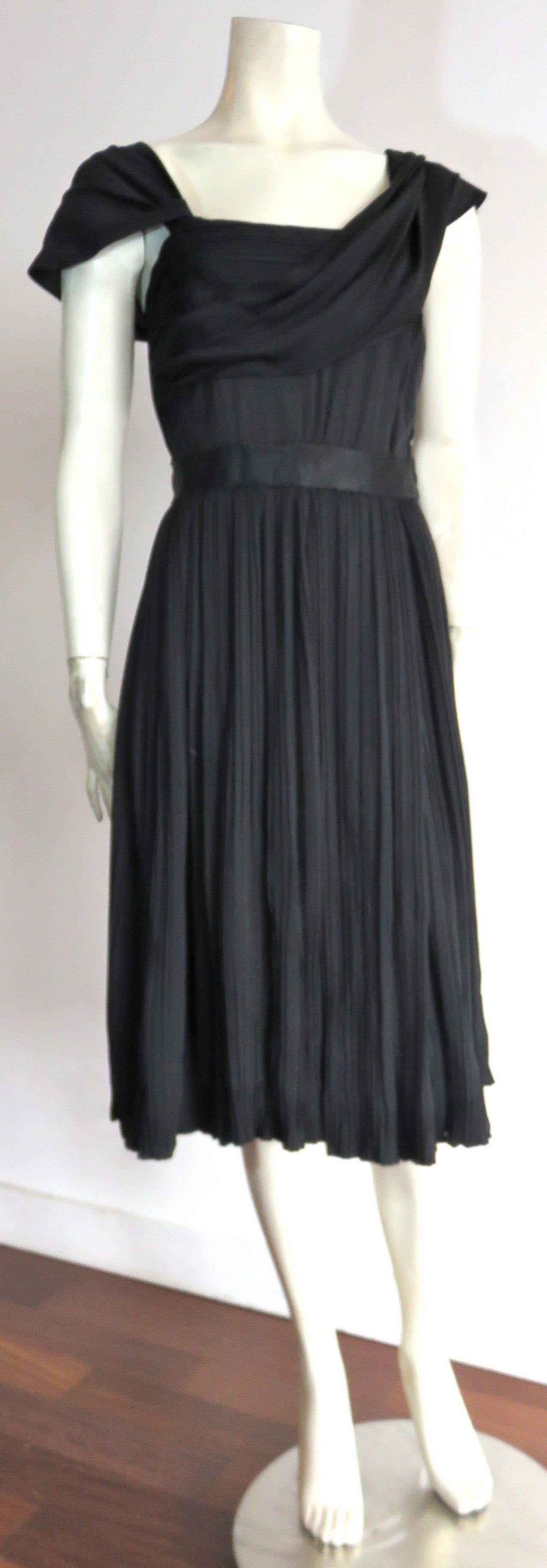 Great condition, 1950's MAINBOCHER, draped, and pleated, black silk cocktail dress.

Gorgeous, draped detailing at the front bust with draped, right cap sleeve.

Satin ribbon waistband with full, pleated skirt.  The top, front, and back bodice