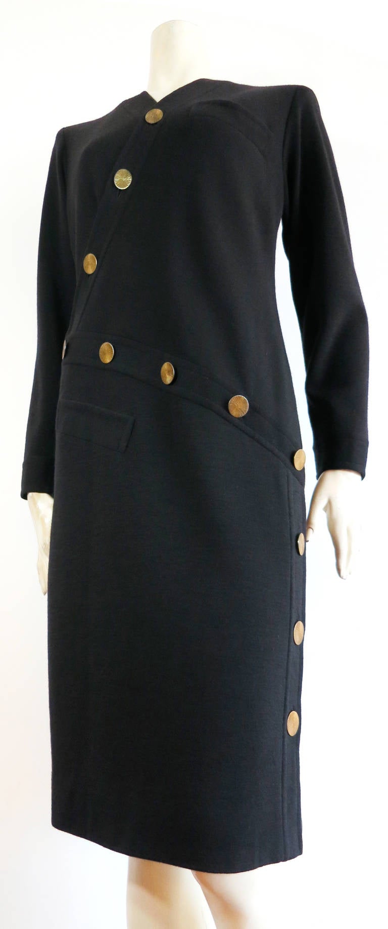 Vintage YVES SAINT LAURENT COUTURE Asymmetrical disk button day dress.

The dress is made of black, wool knit jersey with large, brass metal, disc buttons.

The top of the dress features an asymmetric, 'V'-neck opening.  The disk buttons at the
