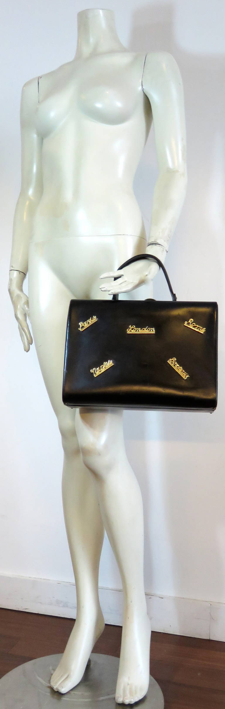 Adorable, 1950's 'Destination' black leather box travel purse.

Black leather, hard box purse featuring gold finished, metal script destination locations, 'Paris', 'London', 'Rome', 'Naples', and 'Bordeaux'.  1950's Jet-set flair.

Metal lock