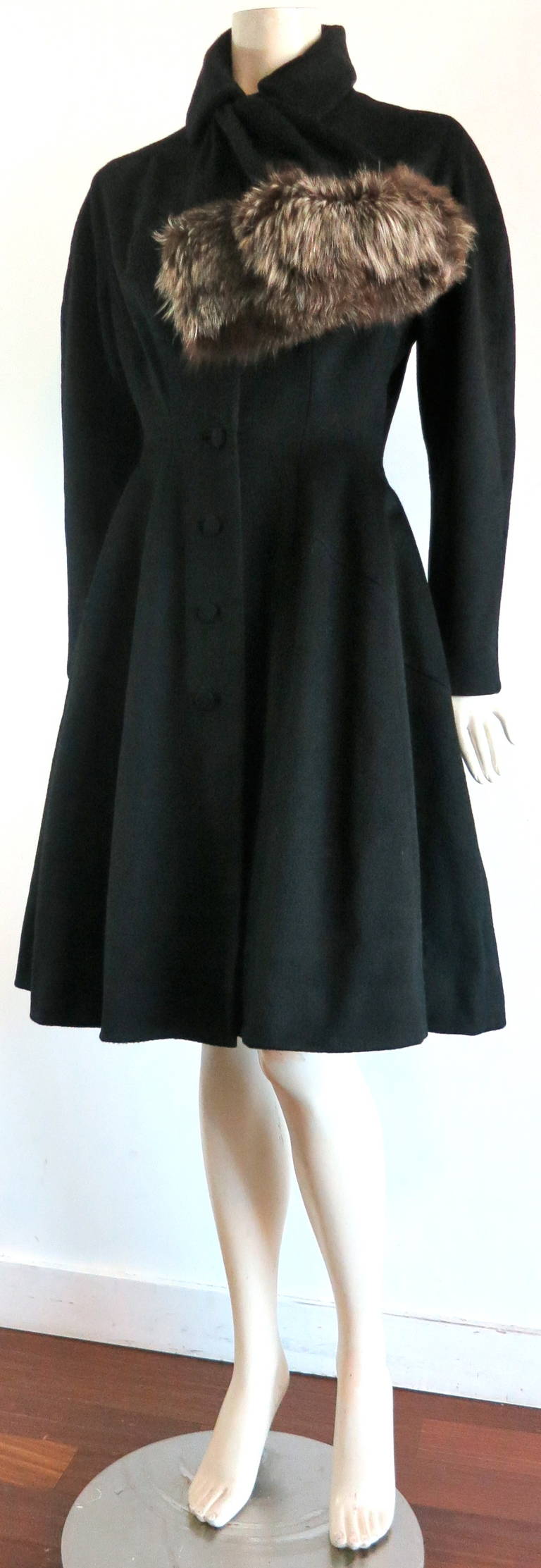 1950's LILLI ANN Black wool coat with fox fur trim.

This adorable coat was designed by Adolph Schuman during the late 1950's to early 1960's.

Made of thick, french, black wool fabrication with genuine, silver-tipped fox fur trim at front scarf