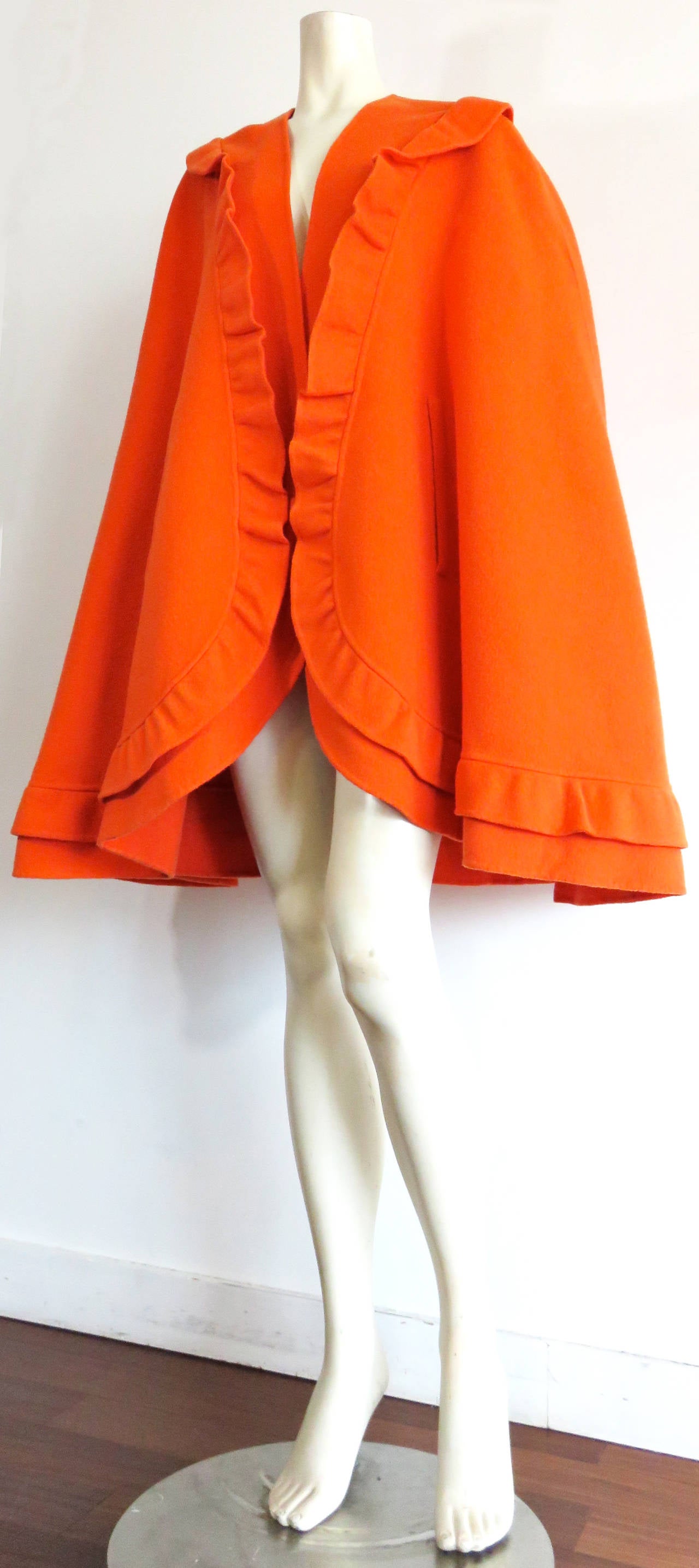 Excellent condition, 1980's MILA SCHON tangerine wool, ruffle detail cape.

Gorgeous curved hem shape with ruffle detail border.

Open-front design with waist-level, hand slot openings.

Made in Italy, as labeled.

In excellent condition