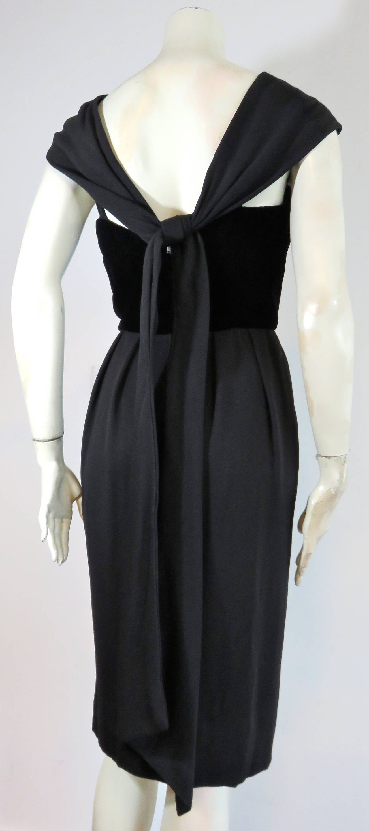Stunning, 1960's LUIS ESTEVEZ black, crepe & velvet cocktail dress.

Plush, black velvet top bodice with draped detailing at shoulders, and long, sash detail at rear.

Front slit detail at bottom hem.

Concealed, center-back zipper