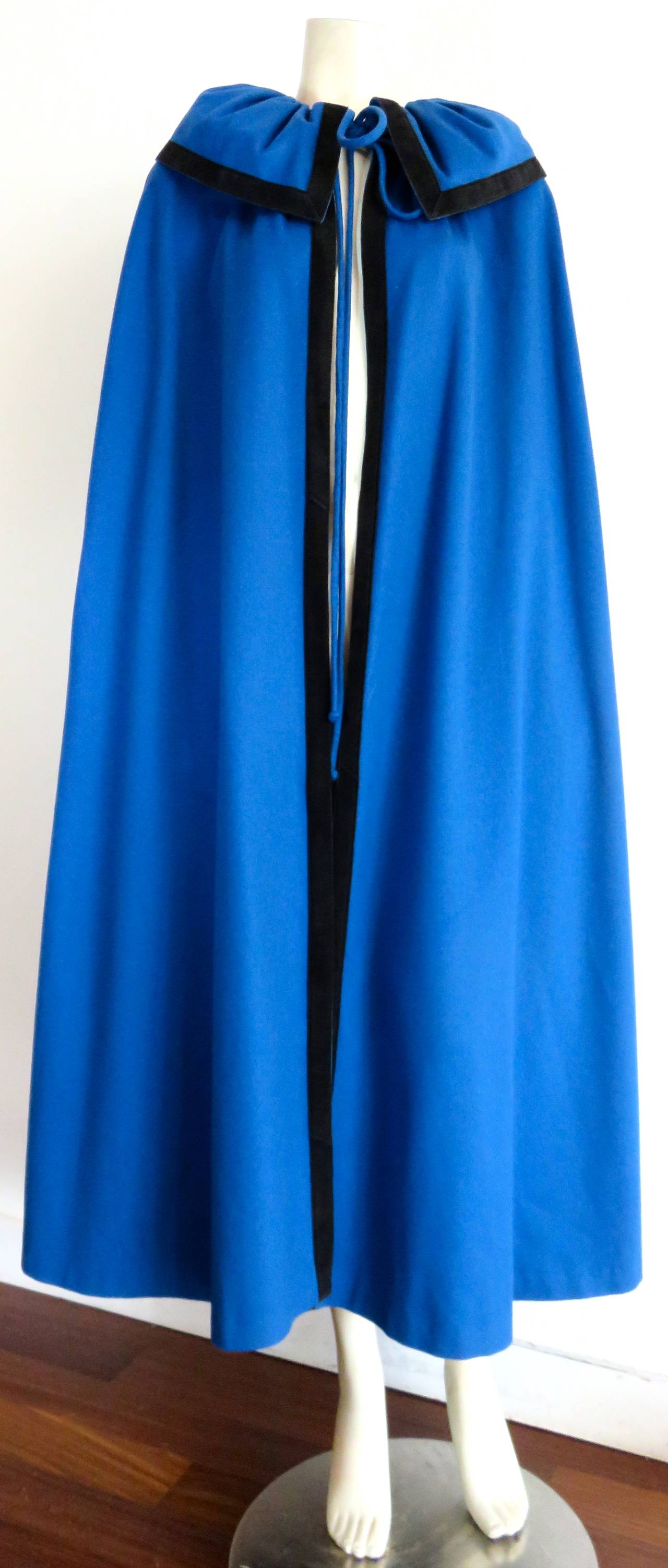 Excellent condition, early 1970's CHRISTIAN DIOR Blue wool & black suede cape.

This gorgeous cape is made of vibrant blue wool with thick, black suede skin edge binding at the collar edge, front opening edges, and sides.

Mitered suede edge