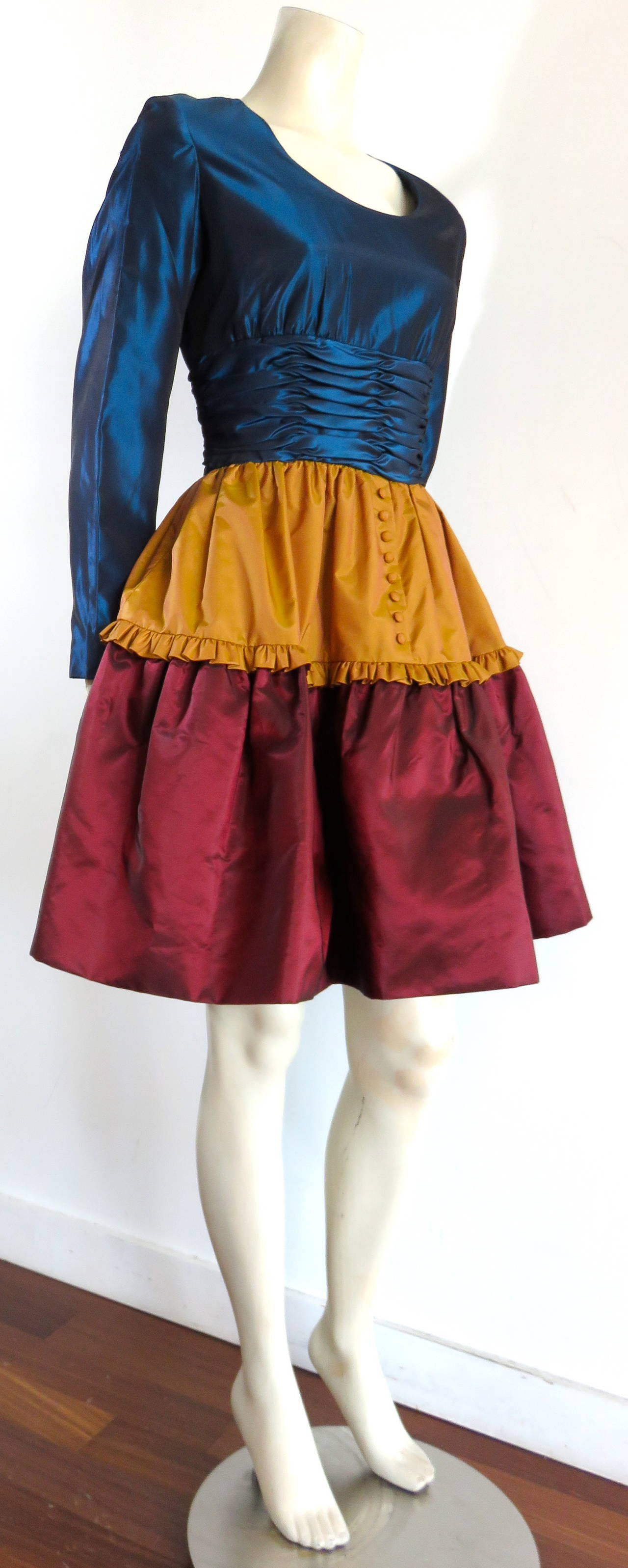 Never worn, 1980's OSCAR DE LA RENTA STUDIO Taffeta cocktail dress.

This lovely dress features shiny, taffeta fabrication in dark teal blue, matte bronze, and dark cranberry red.

The top torso, bodice features pleated construction at the
