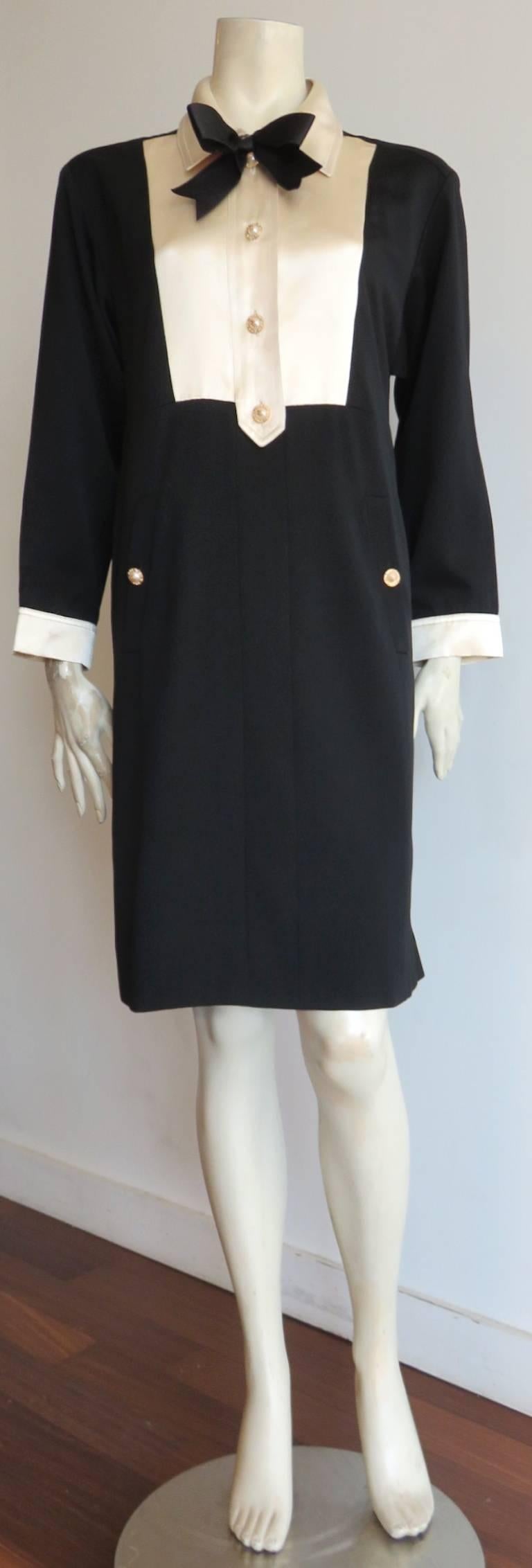 1980's, CHANEL BOUTIQUE, silk, bib-front, 'tuxedo' dress.

Black wool shell with ivory silk bib front, collar, and cuffs. 

Silk, black ribbon bow detail at front neck. 

Faux-pearl, gold rimmed buttons with metal, 'CC' logo center.

Twin