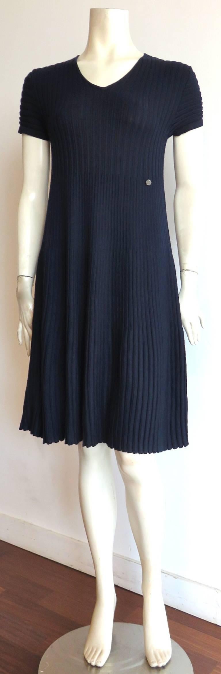 Excellent condition, CHANEL PARIS, dark blue, wool rib-knit day dress.

The dress is fitted in the torso, and flares out with alternating rib-knit gauges down the length of the dress.

Logo engraved, metal plate detail at the wearer's left