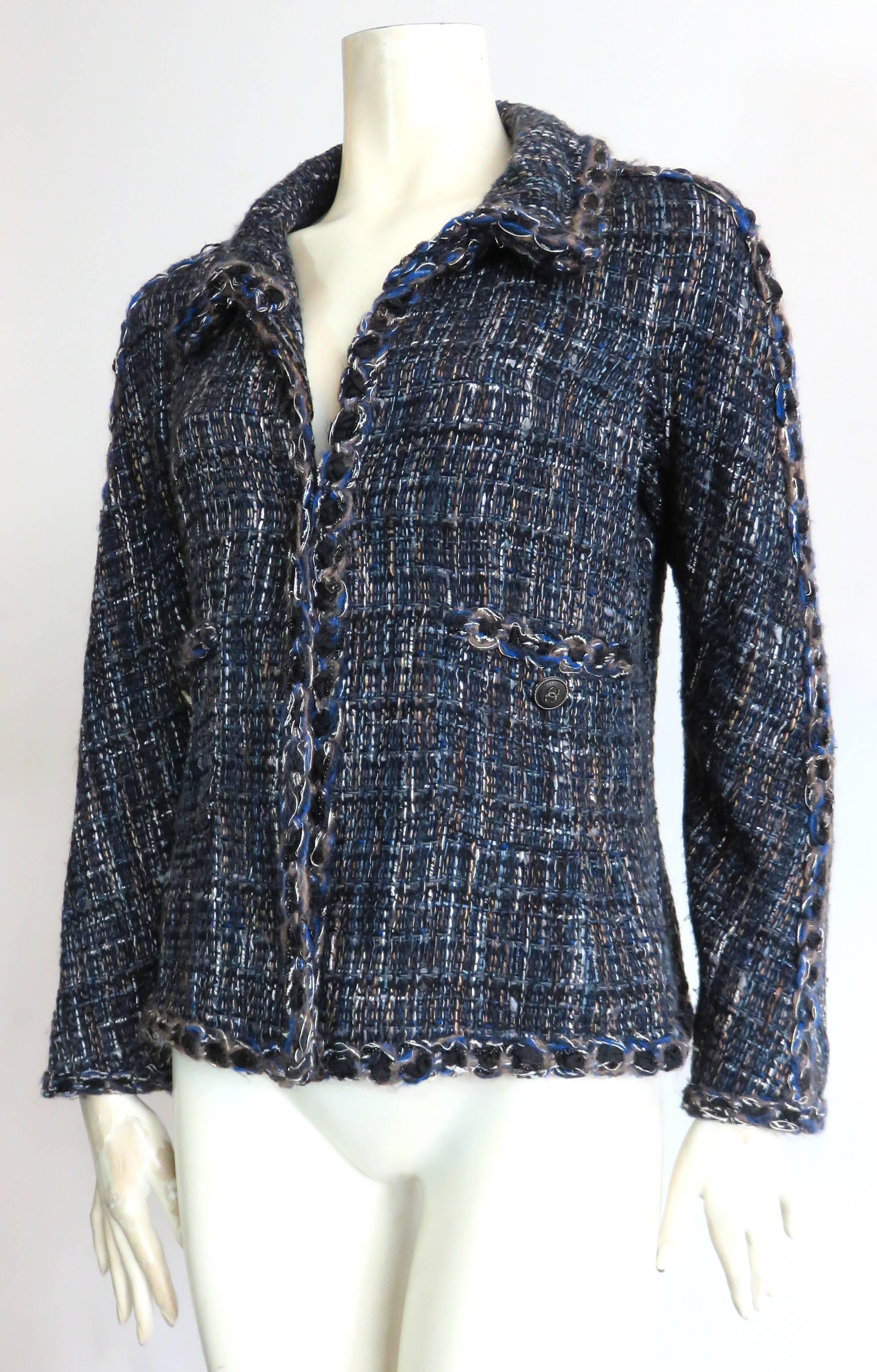 CHANEL PARIS Novelty tweed, open-front jacket featuring multi-yarn detail braiding at edges.

Multi-color, woven tweed ground in black, teal, gray, white, and purple-tone blue.

The outer edges of the jacket feature novelty braid detail composed