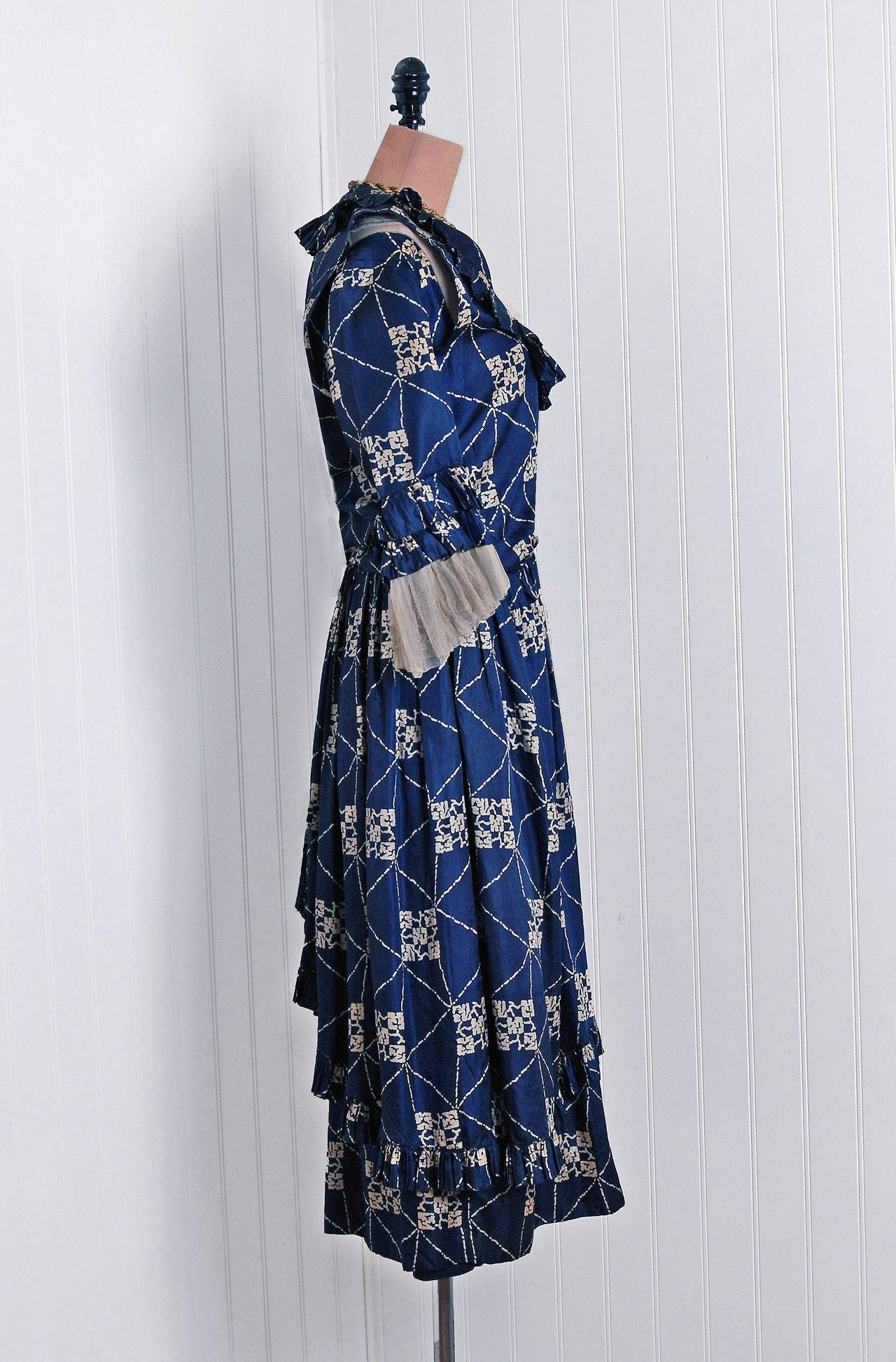 Beautiful 1920's French day dress fashioned in the prettiest navy-blue deco print silk. I love the ivory net-tulle accents and beautiful couture detailing. The bodice is complete with an elegant bib-collar and poet-style tiered ruffle sleeves. It is