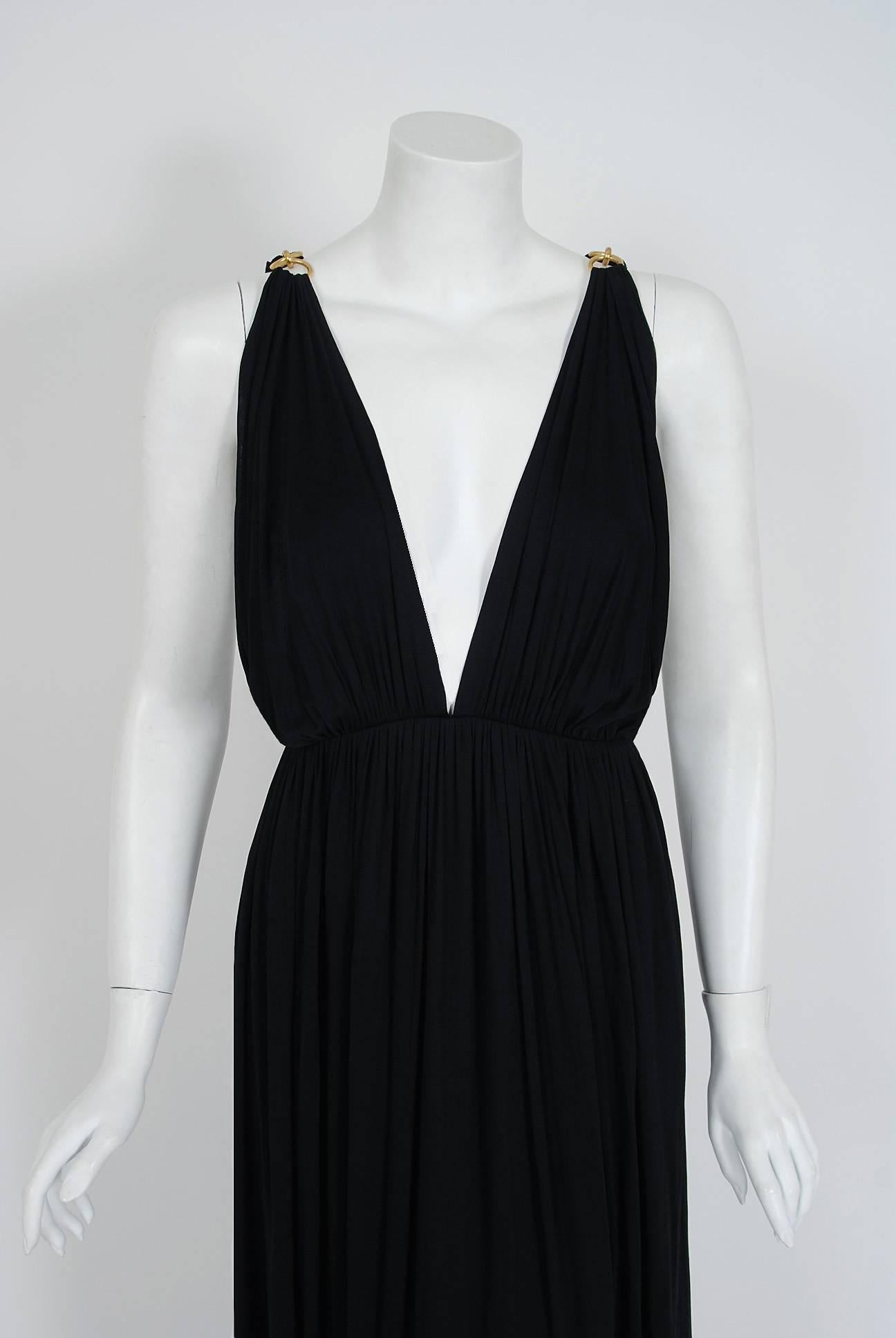 Seductive black rayon-jersey evening gown from the infamous Yves Saint Laurent Rive Gauche collection of 1977. Pieces from this decade are very rare and are true examples of fashion history. I love the breathtaking gold hardware links plunging