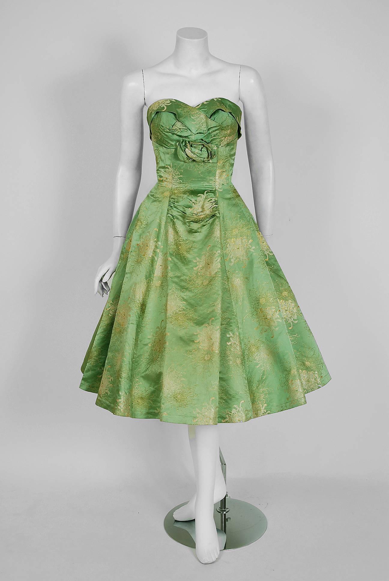 In this gorgeous 1950's sage-green metallic floral party dress, the detailed construction and meticulous attention to detail are comparable to what you will find in modern couture. This enchanting garment is fashioned from shimmering silk-brocade in