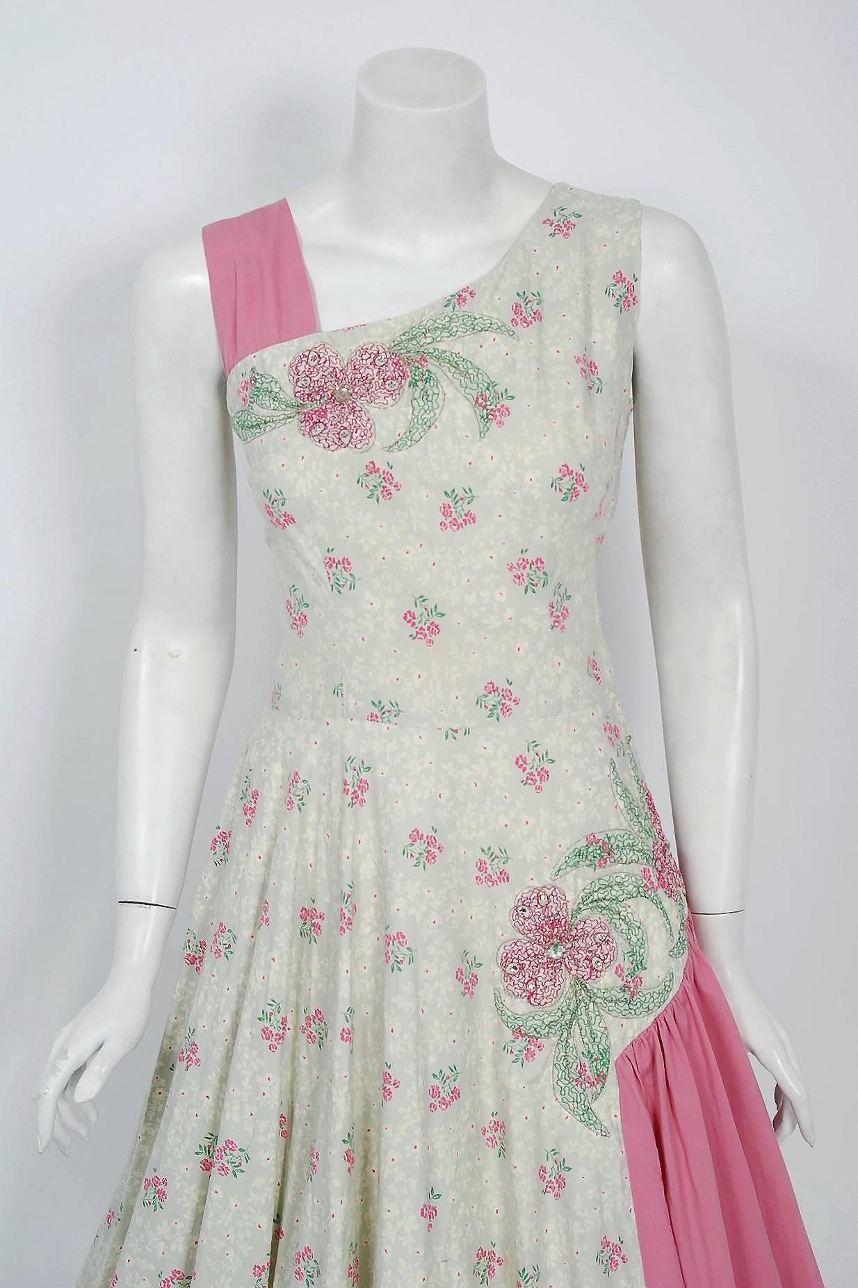 An exceptional and breathtaking 1950's floral cotton sundress by Miami Casuals! The print is an ethereal floral-garden in shades of pink, green, ivory and pale grey. Some of the flowers are actually 3-dimensional; padded from behind and then