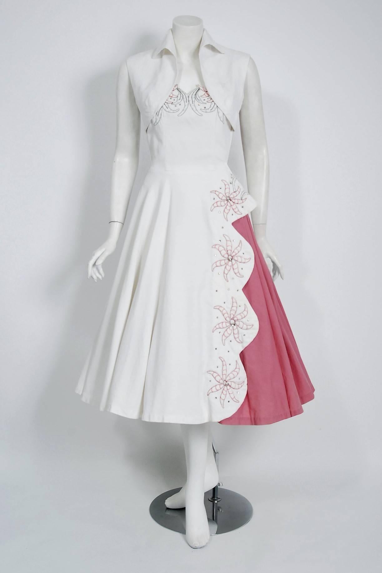 An exceptional and breathtaking 1950's sundress ensemble by Miami Casuals. The fabric is a gorgeous textured white cotton-pique with floral embroidery in shades of pink and green. The large scale flowers are actually 3-dimensional; padded from
