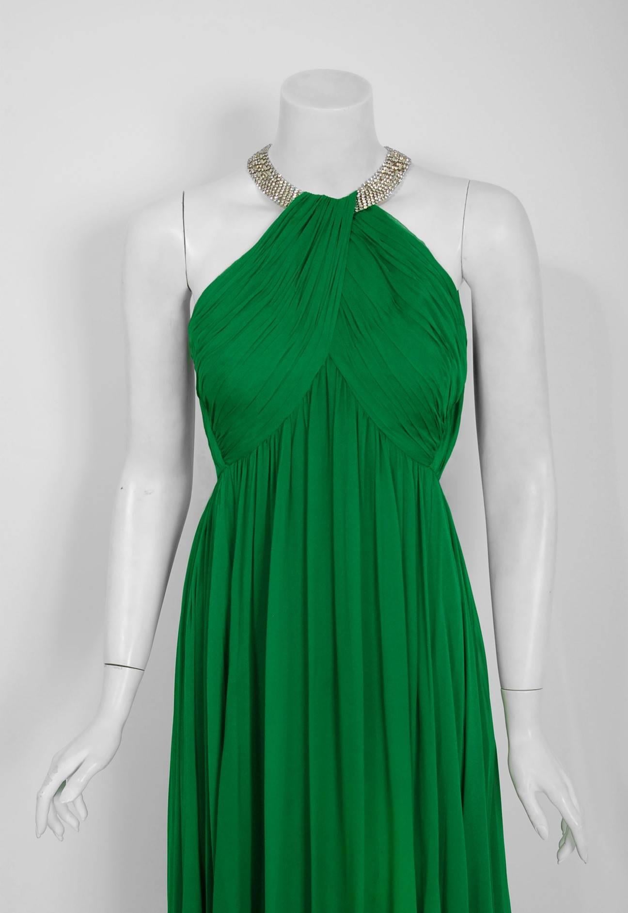 With the sparkling rhinestones and vibrant emerald-green color, this dazzling 1960's Malcolm Starr evening gown does not disappoint. The substantial weight of the layered silk-chiffon fabric whispers high-end luxury. The bodice is an elegant