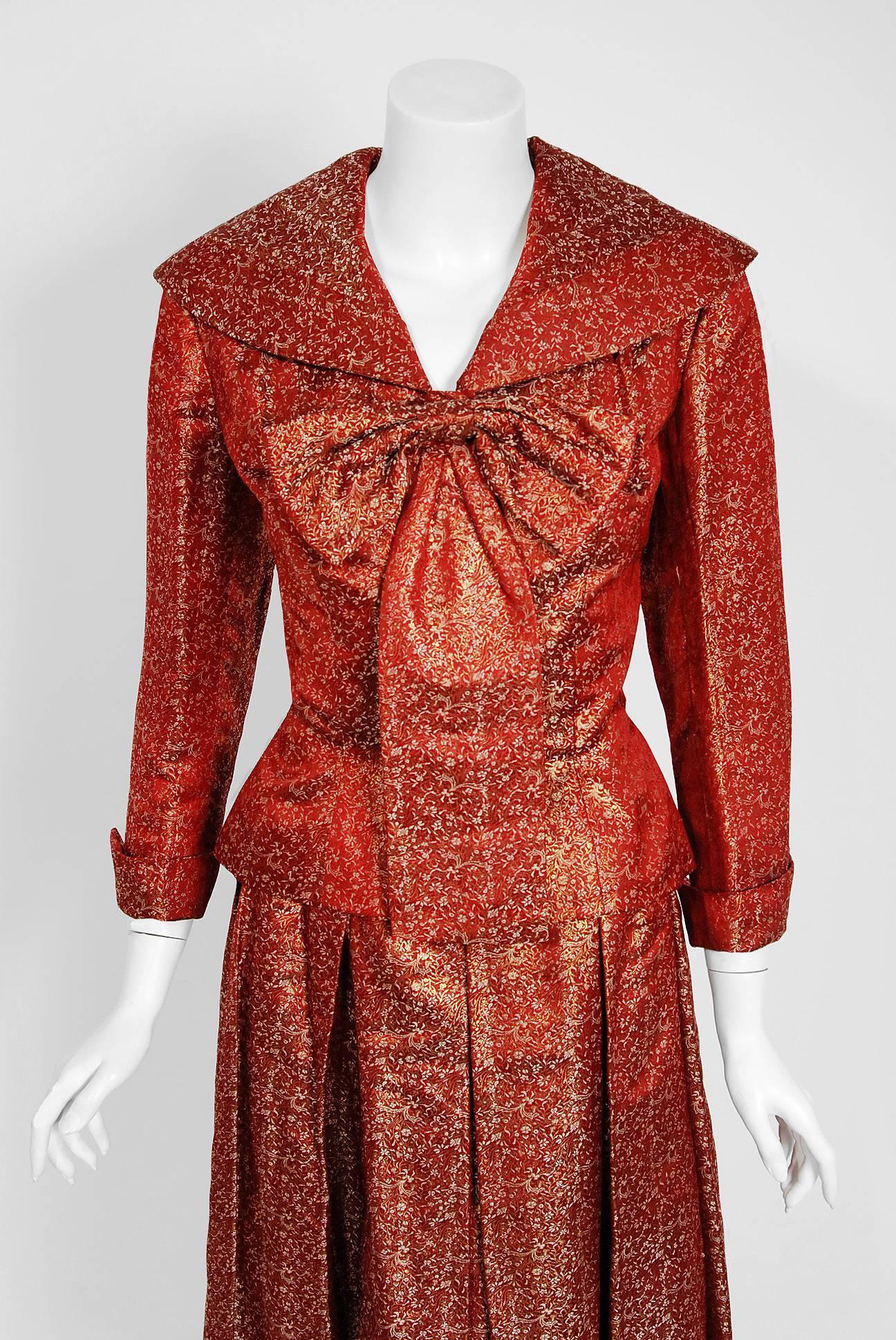 This stunning Salama Haute-Couture ensemble, dating back to 1952, is fashioned in burgundy red fully-lined leaf motif silk brocade. The fabric itself is a masterpiece; vertical woven metallic gold accented silk that seems to have an almost