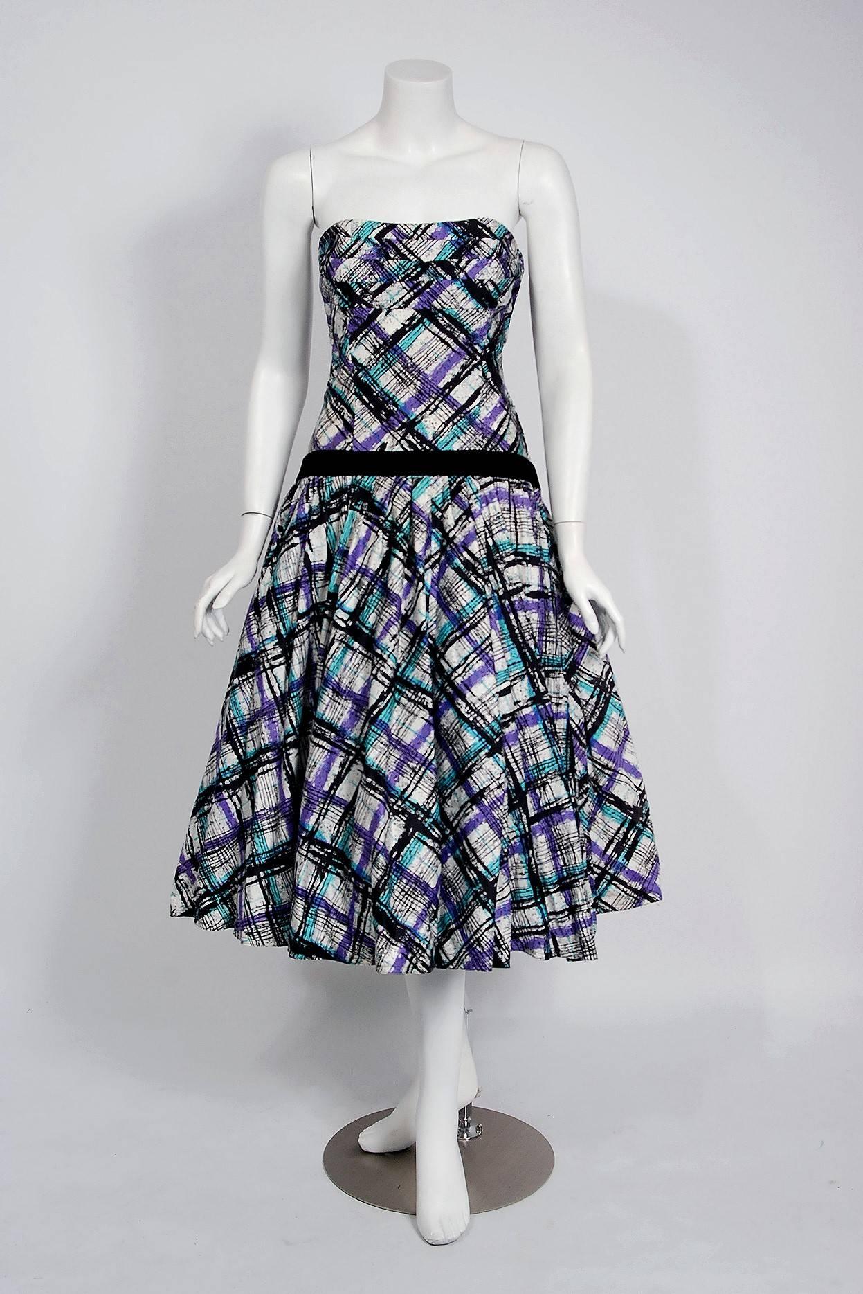 In this gorgeous 1950's graphic plaid party dress ensemble, the detailed construction and meticulous attention to detail are comparable to what you will find in modern couture. This enchanting garment is fashioned from turquoise, purple and black