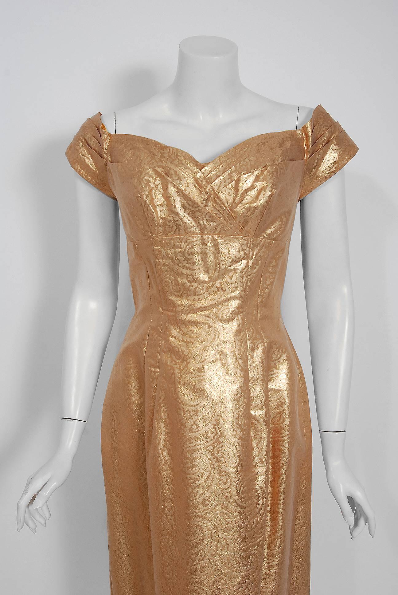 A stunning 1950's custom couture metallic-gold bombshell cocktail from the Old Hollywood era of glamour! The fabric itself is a masterpiece; shimmering paisley floral print golden lined silk lamé. The bodice is an alluring low-cut plunge pleated