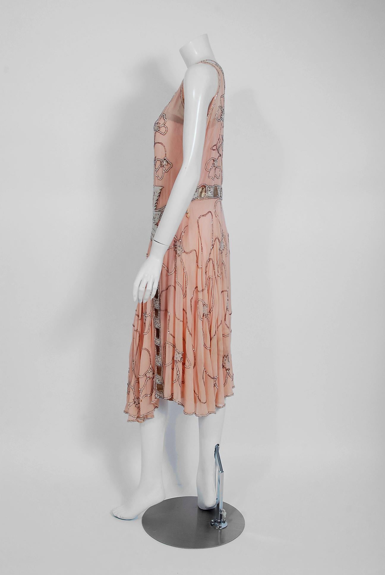 Undiminished by time, this 1920's rose-pink dance dress still casts its magical spell. This exceptional Art Deco beauty is fashioned in three different French couture fabrics- sheer silk chiffon, metallic gold lace and lamé ribbon-weave trim. It is