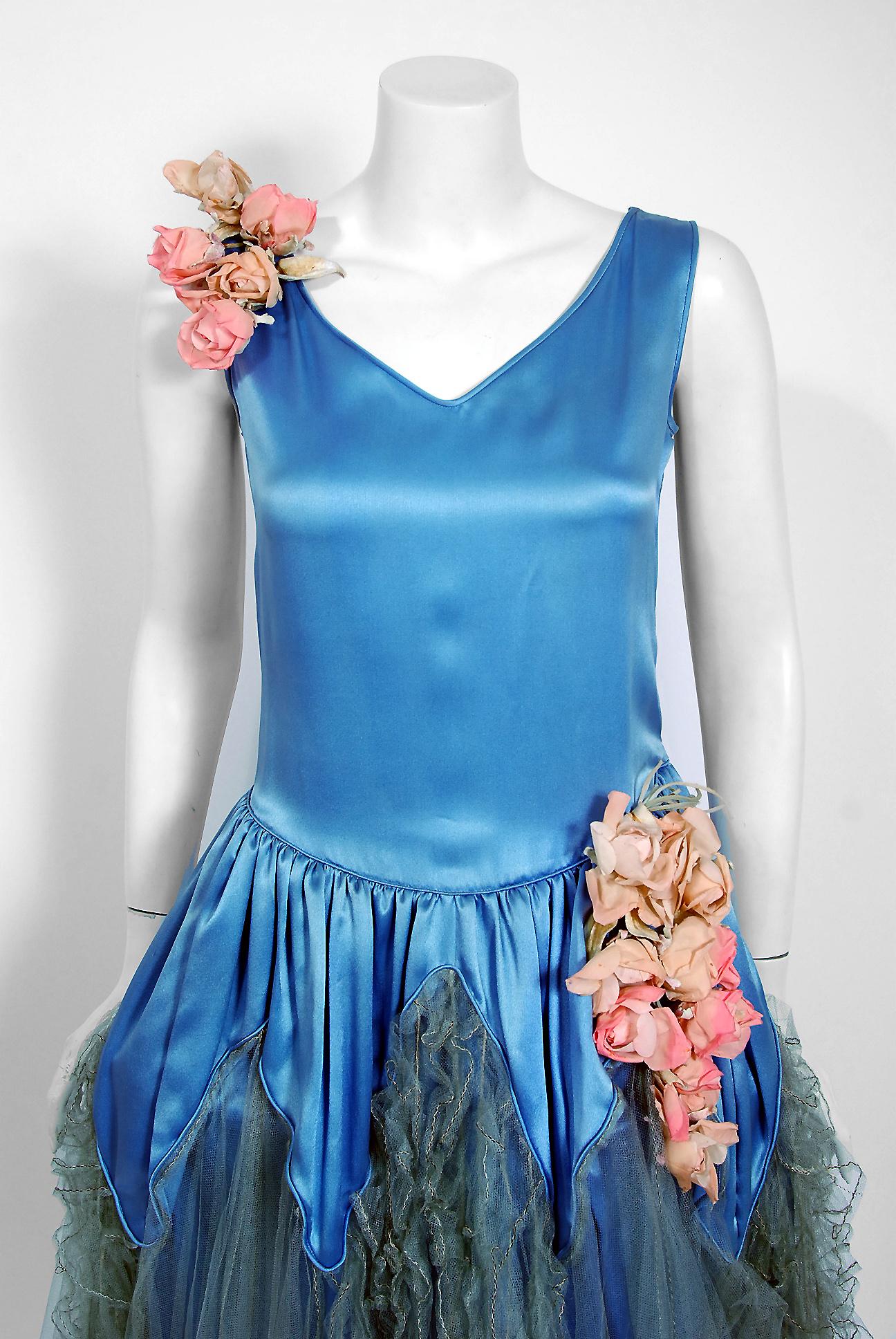 Breathtaking 1920's French dance dress in the iconic 'robe de style' silhouttee made famous by Jeanne Lanvin. The dress is fashioned in luxurious blue silk-satin and sheer tulle. Three dimensional pink rose appliques add the perfect amount of charm.