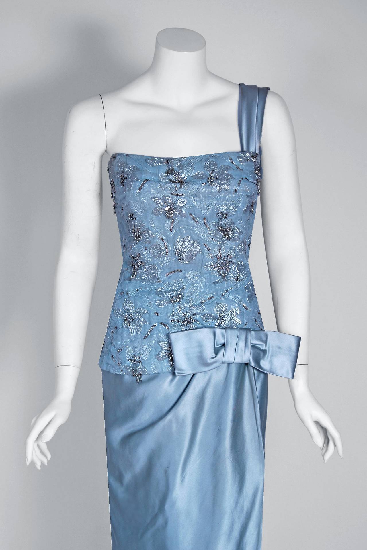 Beautiful ice-blue beaded metallic silk and satin gown by the famous House of Maggy Rouff. Harmony and simplicity were cornerstones of Maggy Rouff's belief in elegance as a way of life, and the way of fashion. A truly elegant woman was in harmony