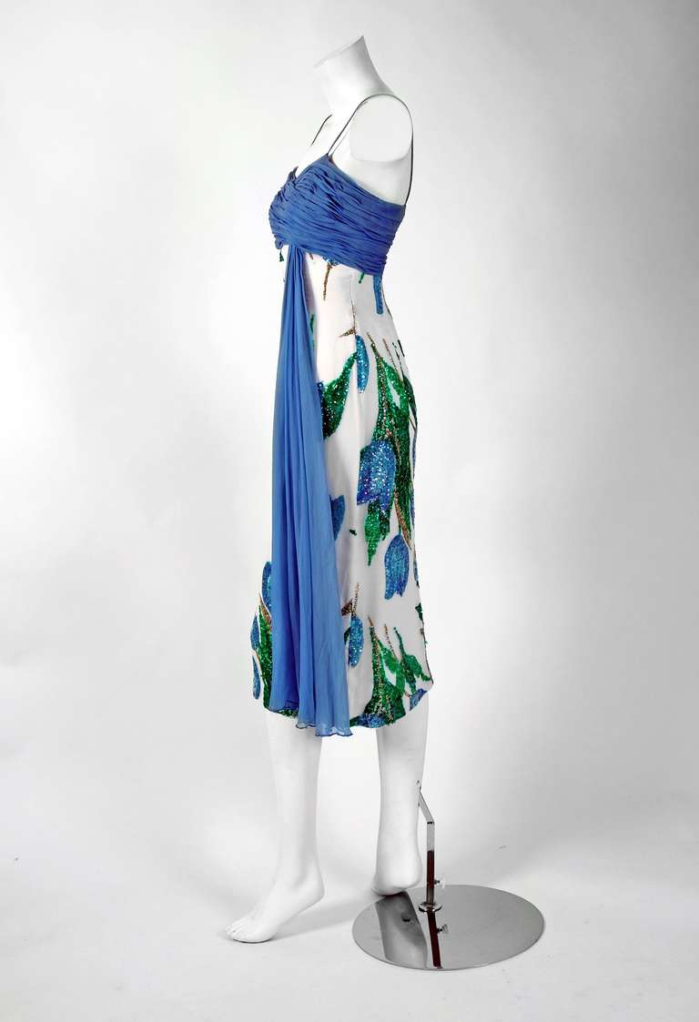 With its vivid blue-tulips watercolor print and flawless hourglass silhouette, this British Crown Colony cocktail dress sold by Norman's boutique in Denver has the casual elegance the 1950's were known for. The fabric alone is unbelievable;