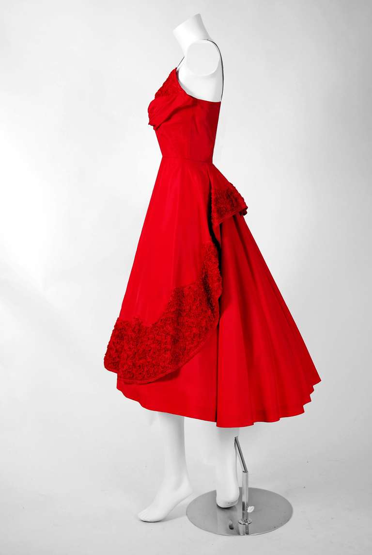This is perhaps the most darling and flattering 1950's party dress I have ever seen. Fashioned from vibrant light-weight red taffeta, this creation has everything a woman wants. The bodice is a stunning thin-strap boned sweetheart plunge design. The