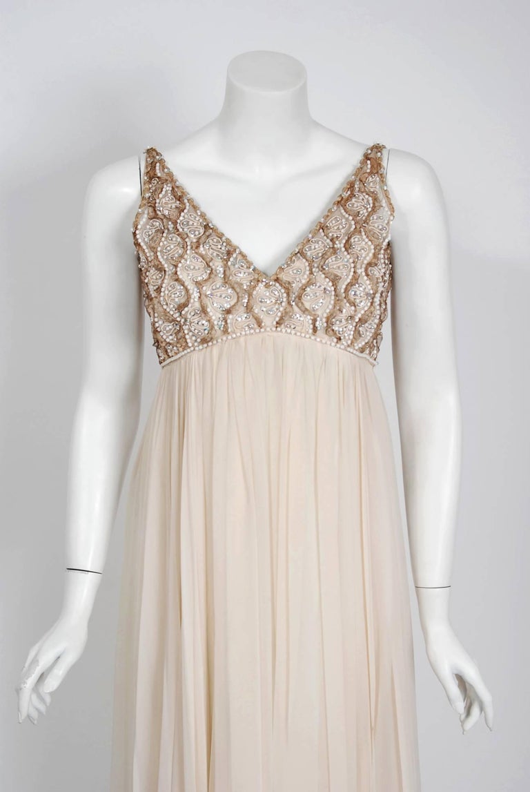 With the sparkling embellishment and ethereal ivory creme color, this dazzling 1960's Malcolm Starr evening gown does not disappoint. The substantial weight of the draped silk chiffon fabric whispers high-end luxury. The bodice is an elegant