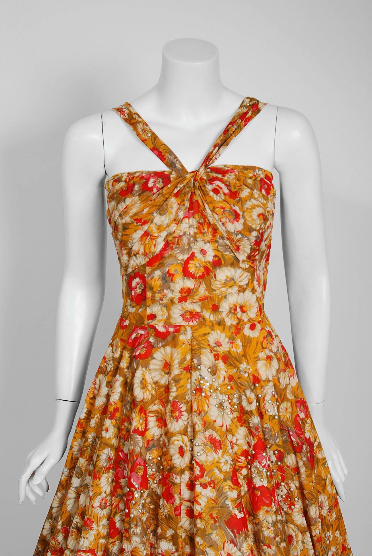 This gorgeous marigold daisies & red poppies floral print sundress by Aywon Originals is the perfect addition to any vintage wardrobe. The bodice has an alluring mock halter sculpted shelf-bust design. The hourglass nipped waistline is both ladylike