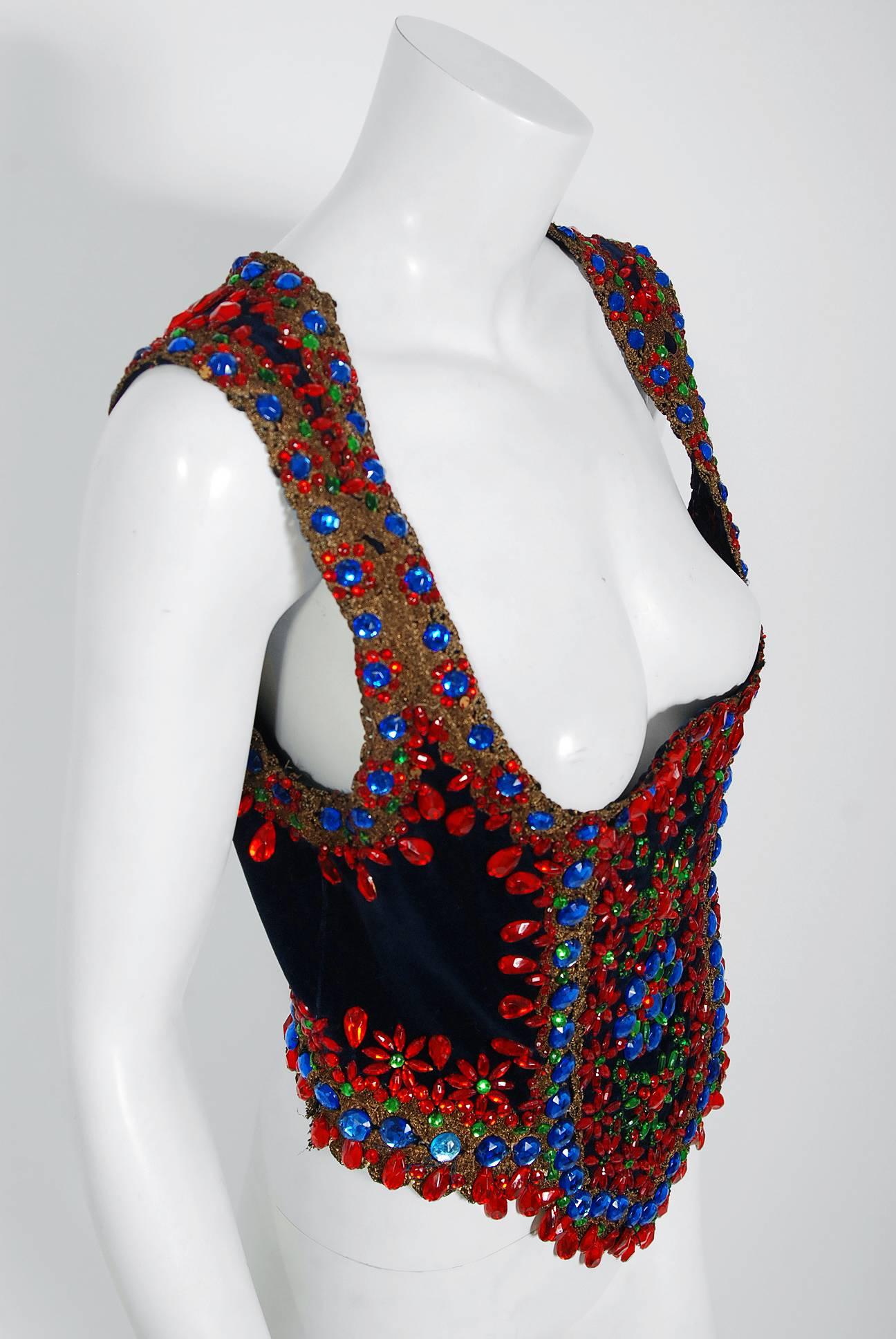 This sensational 1960's custom couture dark navy velvet décolletage bodice is lavishly embellished with red, green, and blue large faceted jewels and sparkling bronzed gold metallic lace.  The highly stylized shape perfectly captures that bohemian