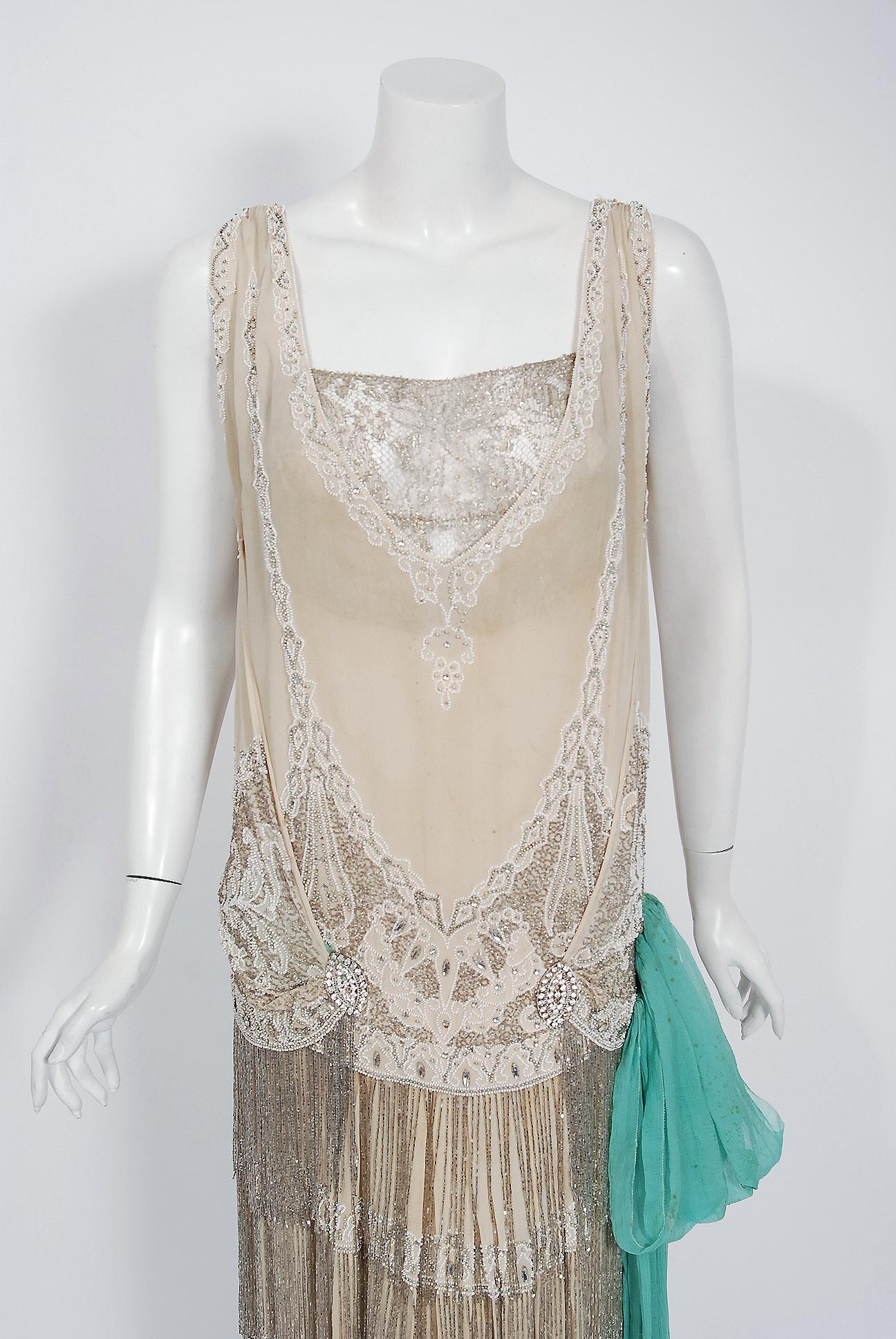 Undiminished by time, this 1920's ivory-creme flapper dance dress still casts its magical spell. This exceptional French beauty is fashioned in three different couture fabrics- creme silk chiffon, metallic gold lace and robin-egg blue silk crepe. It