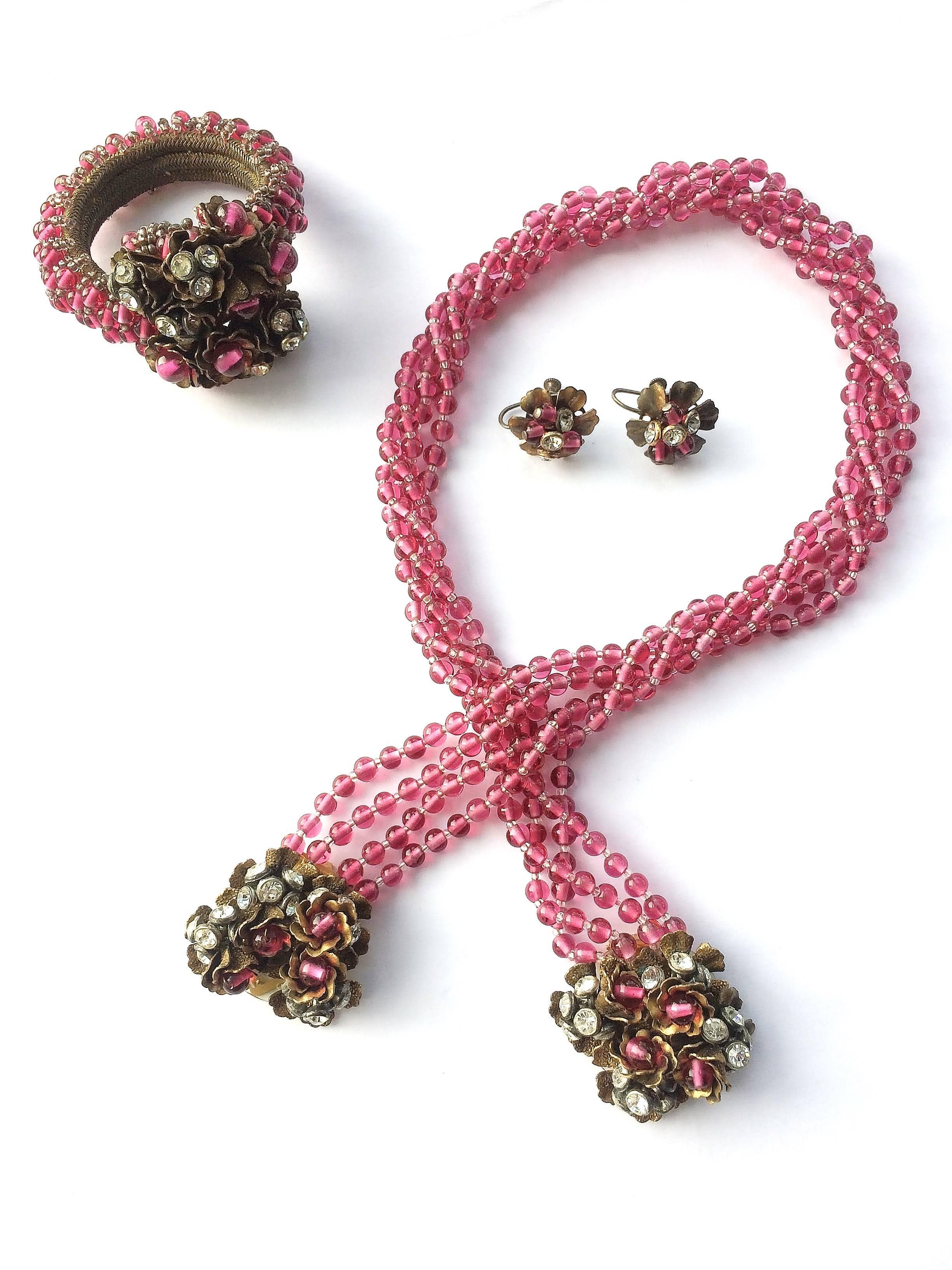 Wunderschöne dreiteilige Parure (Wickelhalskette mit Juwelenanhängern, Wickelarmband und passende Ohrringe), ein ikonisches Design aus den 1930er Jahren von Miriam Haskell. Die Halskette aus weichem cranberryfarbenem Pate de Verre-Glas wird um den