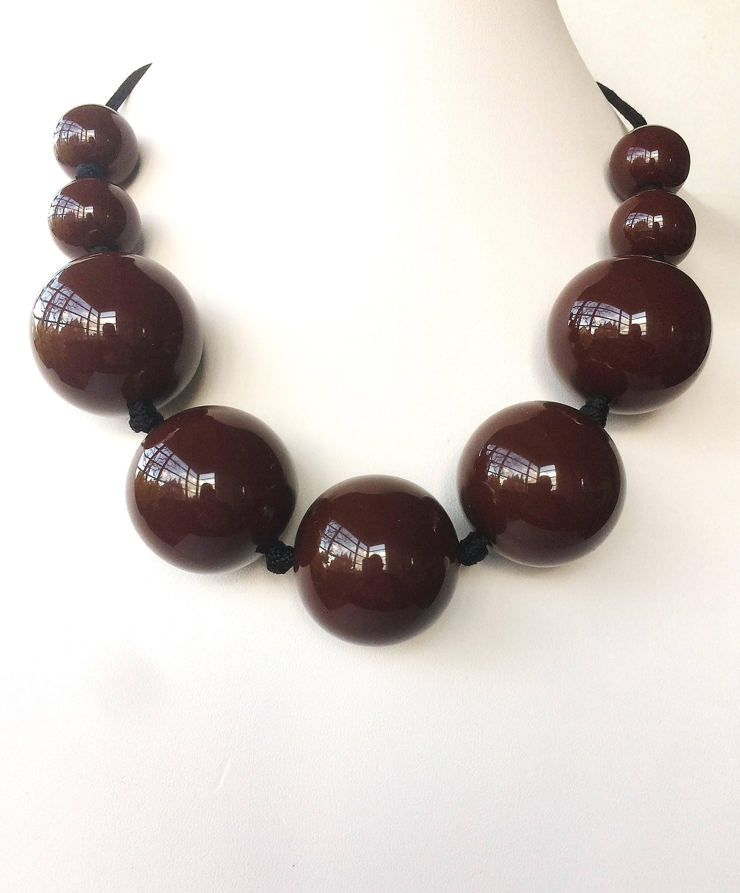 Made from traditional brown lacquer over Japanese hardwood, this graduated necklace of soft, warm coloured and high gloss spheres is one of the iconic designs by celebrated Elsa Peretti for Tiffany & Co. Threaded on finely plaited and woven silk