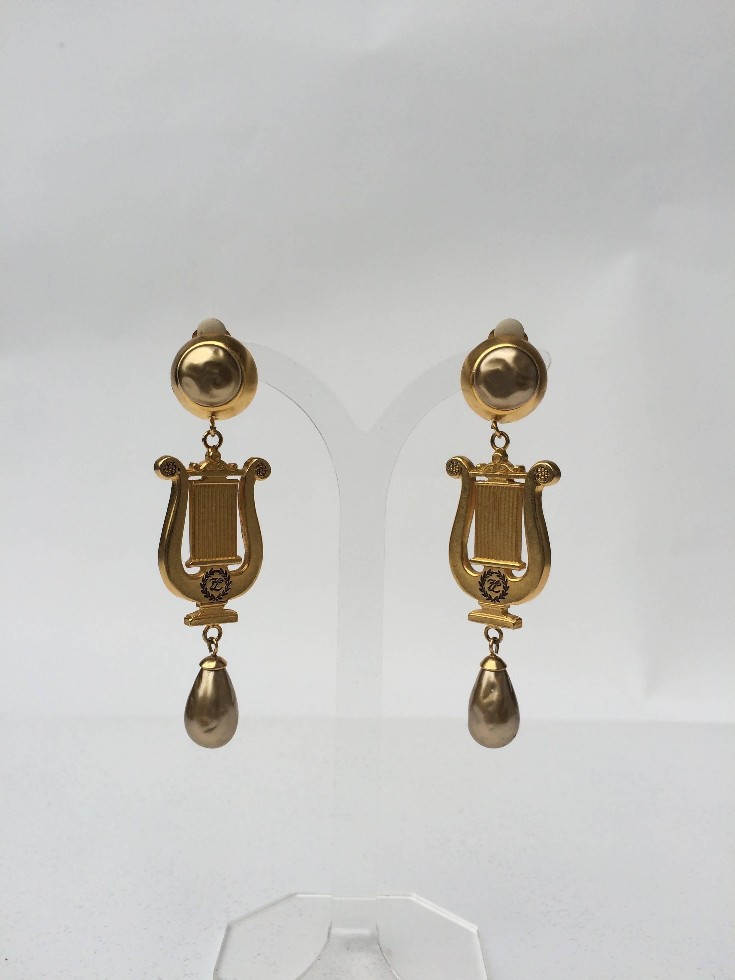 These neoclassical lyre motif earrings have lovely golden hued baroque pearls and dangle down impressively. The signature KL is on the front in very discreet black enamel encircled with a laurel motif. 
High eighties style, these would suit someone