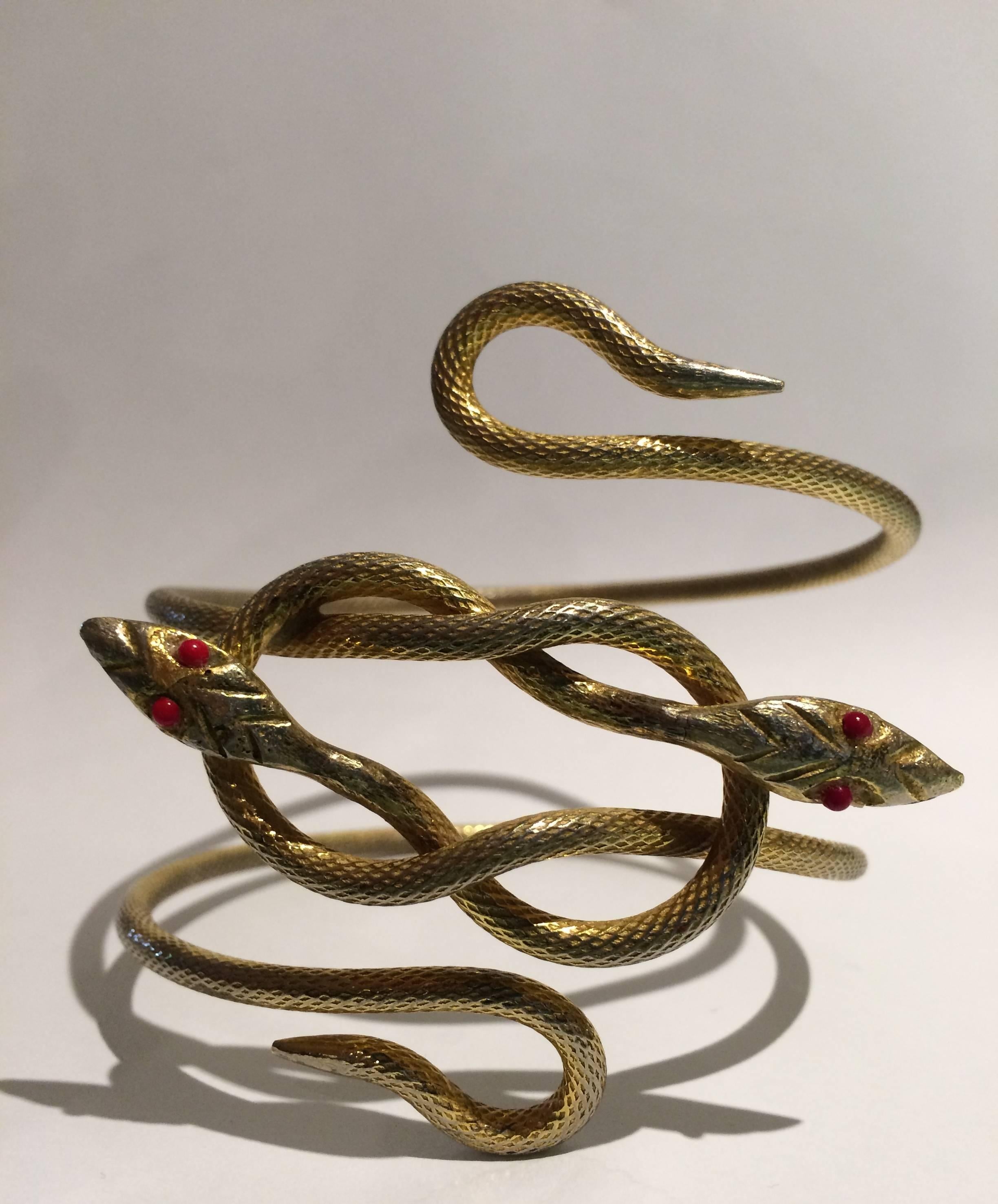This wonderful bracelet is a great rendition of a perennial theme. Normally single, this is a double headed example which makes it rarer. It has a lovely soft lightish gilt patina and fine quality engine turning on the body of the snakes. The heads