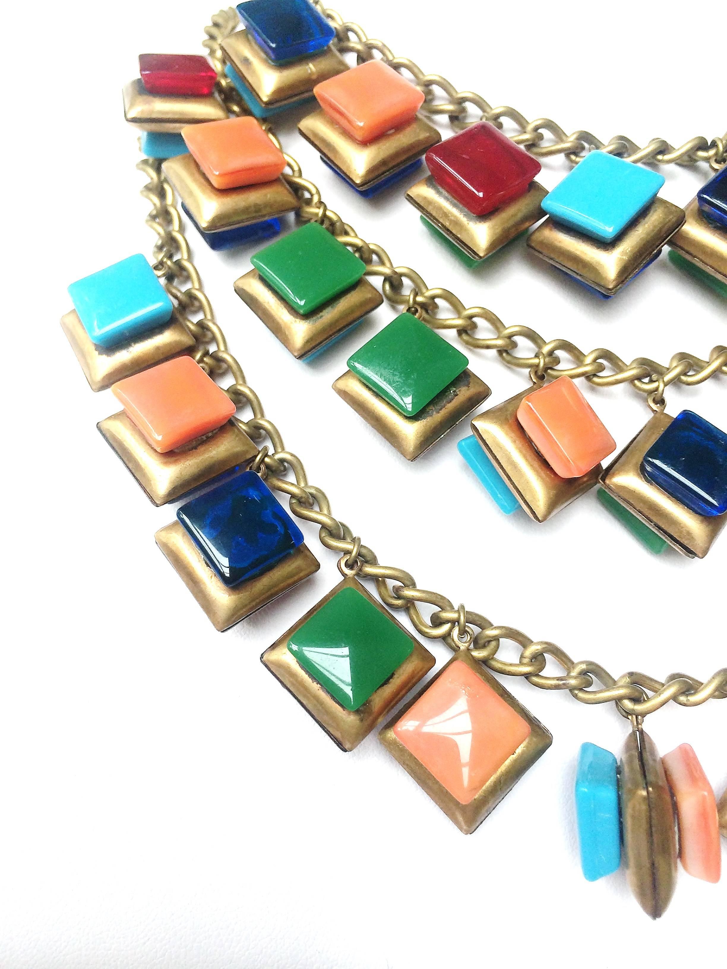Unsigned - but utterly striking, and pleasurable -  a necklace of brass chains with brass 'cushion' charms suspended, each 'charm' embellished with a coloured square of glass, both opaque and clear, in an assortment of hues.This dramatic piece has