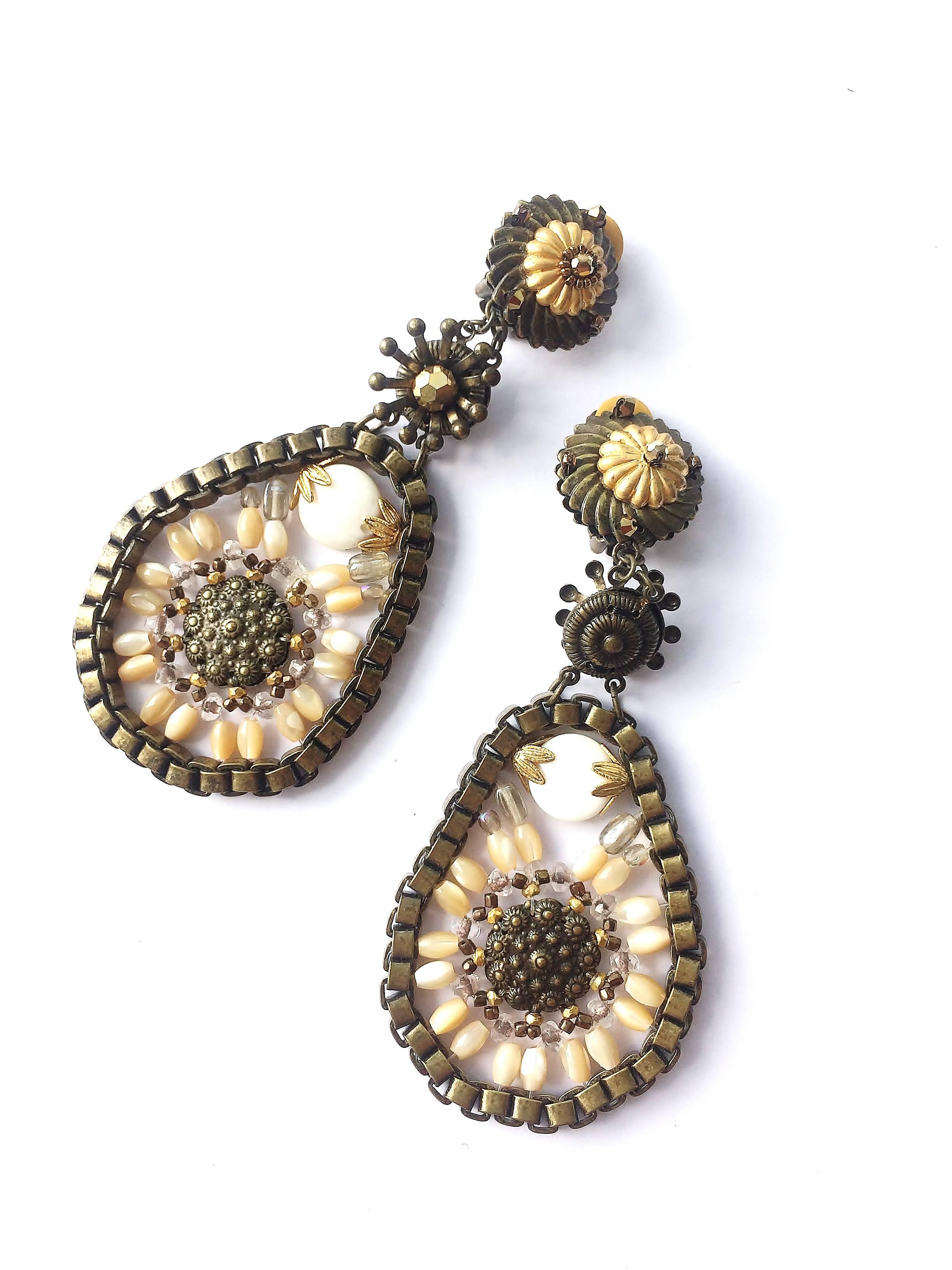 Dynamic and funky drop earrings from the 1990s by Miriam Haskell,in a soft gilded metal, with white and clear glass beads, and imitation pearls. A somewhat more modern and contemporary look from this designer, these earrings have a great appeal for