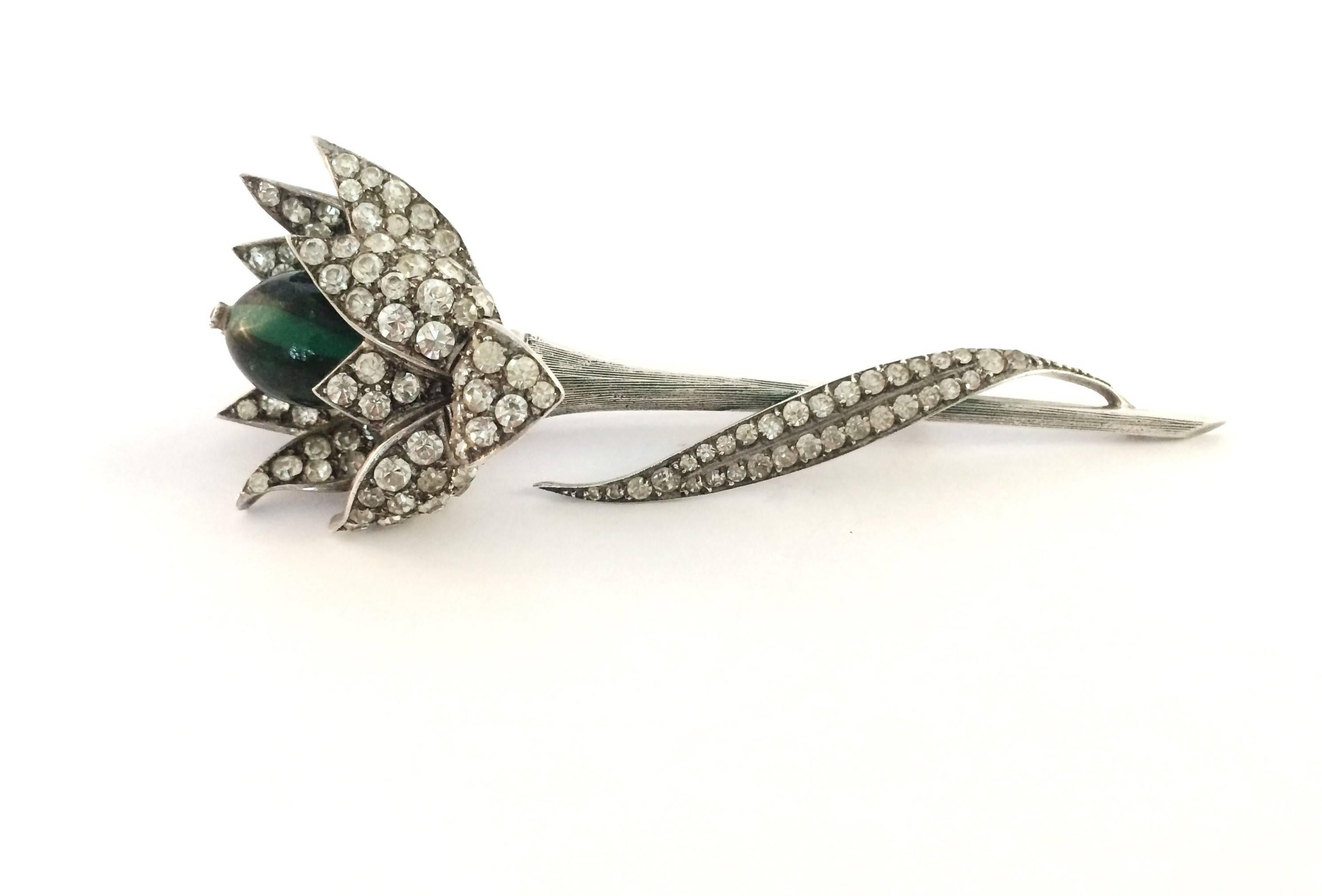 This beautiful and elegant brooch is from the Yves Saint Laurent period of the House of Dior, part of a very small and exclusive collection made in sterling silver and paste. Set with a large glass emerald cabuchon, highlighted with a single paste