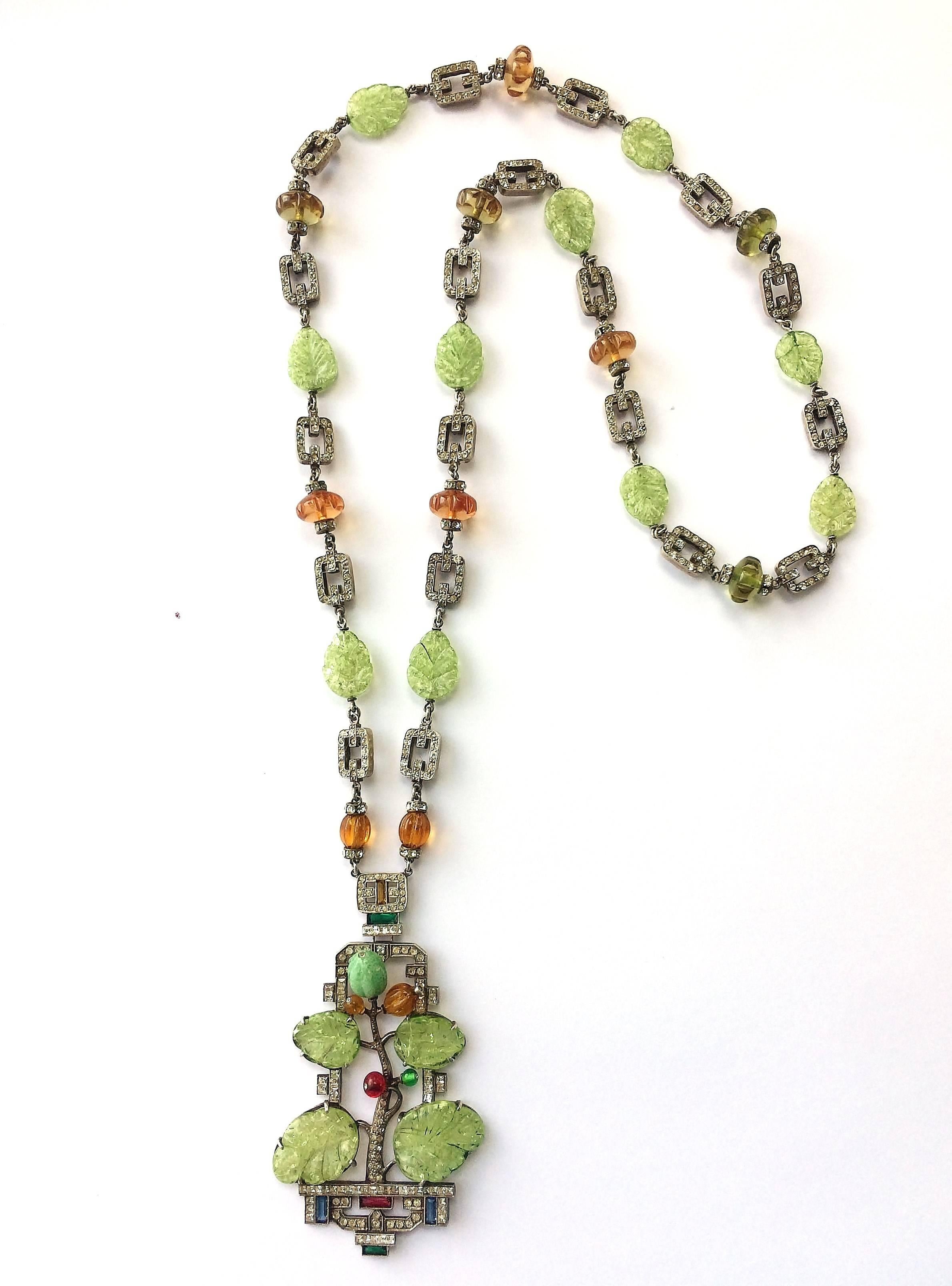 A fabulous and very long sautoir pendant necklace, whose chain is composed of double sided soft rectangular set in sliver with pastes, interspersed with melon cut topaz and peach beads and moulded glass light green 'leaves'. The dynamic pendant is