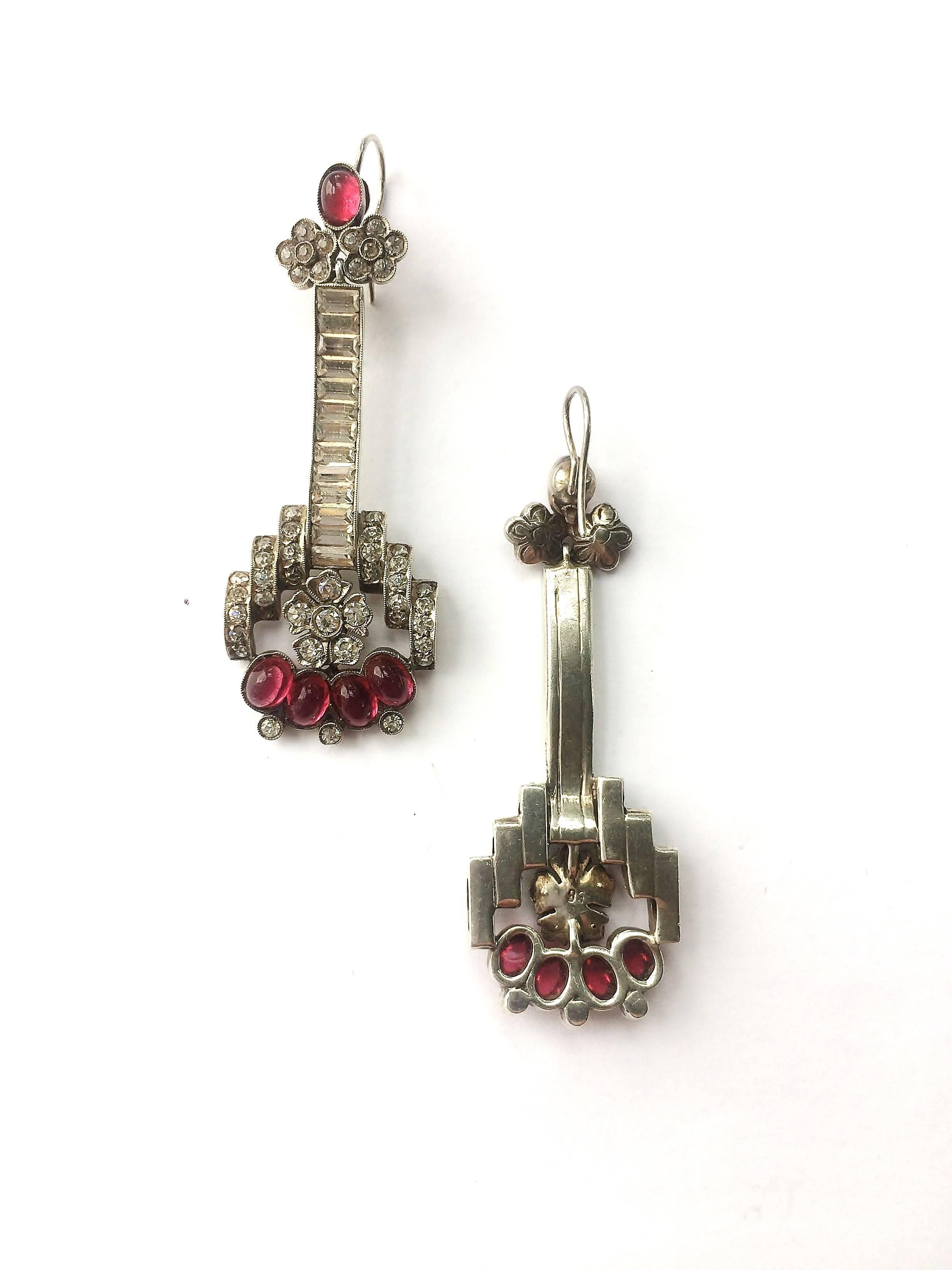 Exquisite and highly stylised sterling silver and clear paste drop earrings, with ruby cabuchons, with a silver hook fitting for pierced ears, from the 1930s. They are stamped '935'.
A simple piece with pave set clear paste baguettes make the large