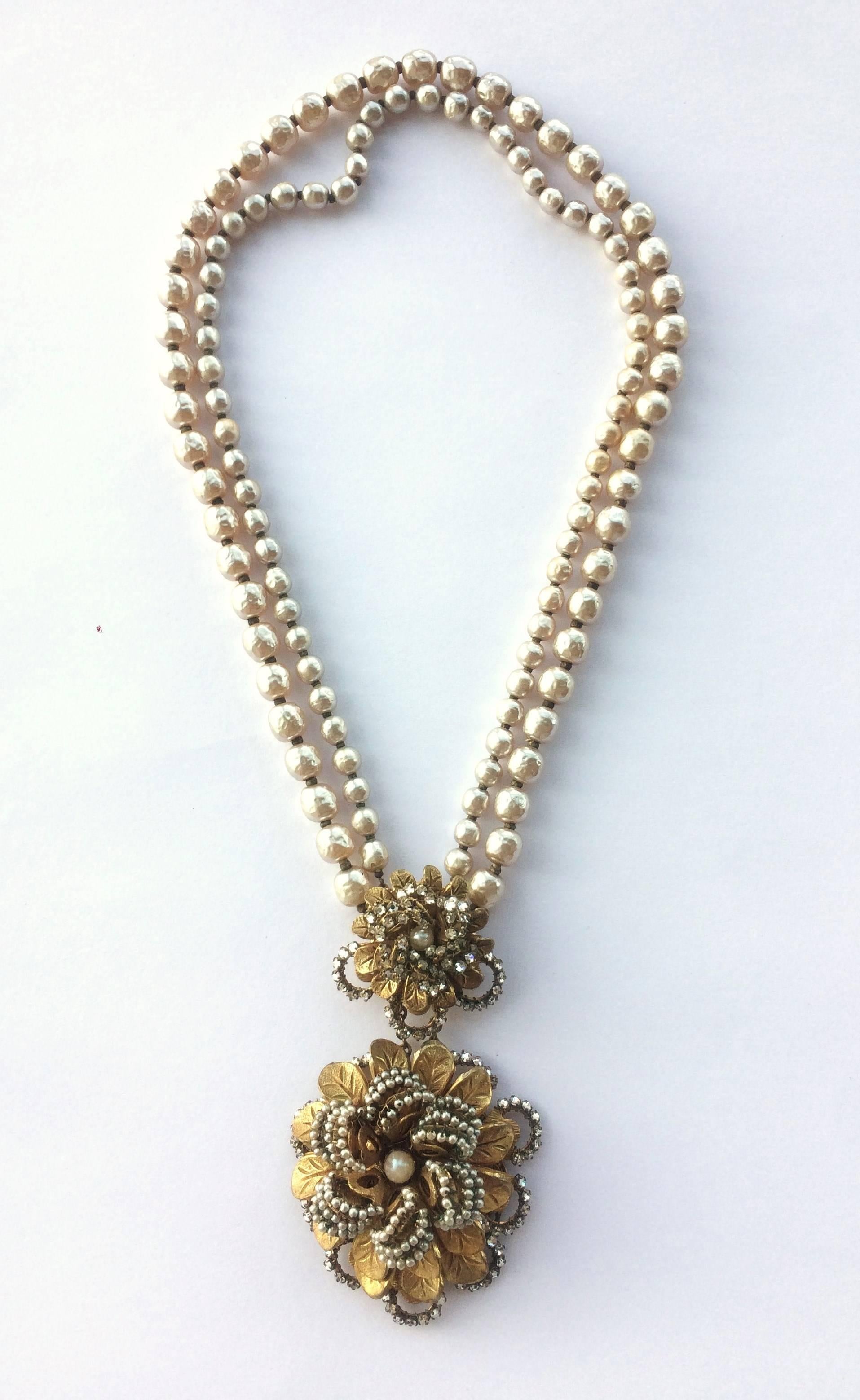 Designed by Frank Hess for Miriam Haskell, this 2 row baroque pearl necklace has a double rosette centrepiece at the front, encrusted with seed pearls and rose montes pastes, with gilded leaf detail. A lovely length, and beautiful example of early