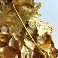 Spilla "maschera" in metallo dorato, Maison Goossens, anni '90, Francia.