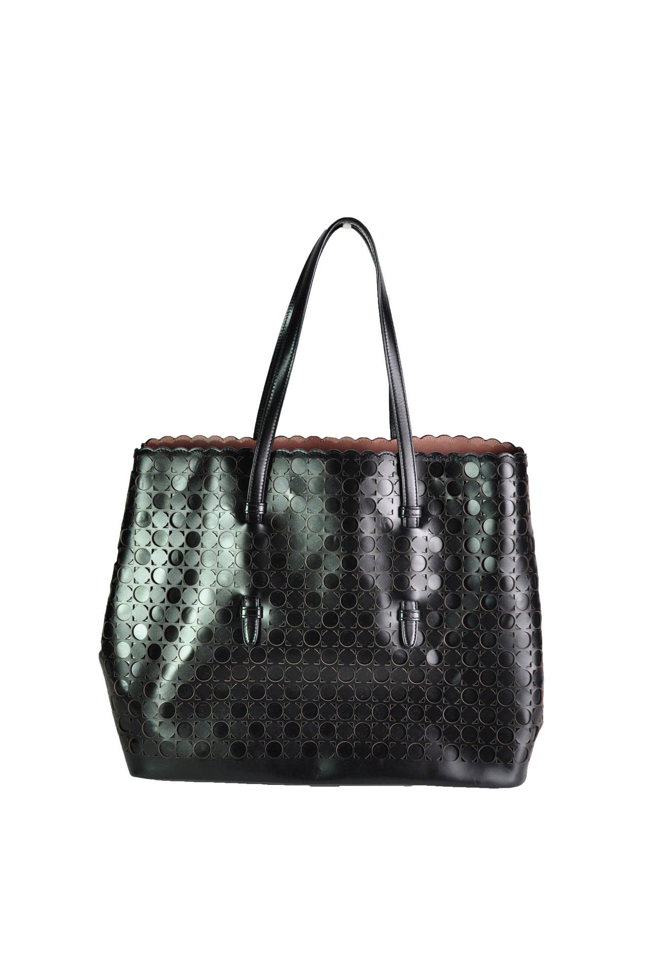 Black calf leather shopper tote from Alaia features with a scalloped top closure and expandable snap fastening sides. Dual handles on top, cut out patterned detailing to the front and rear with the iconic blush-hued interior. Comes with a detachable