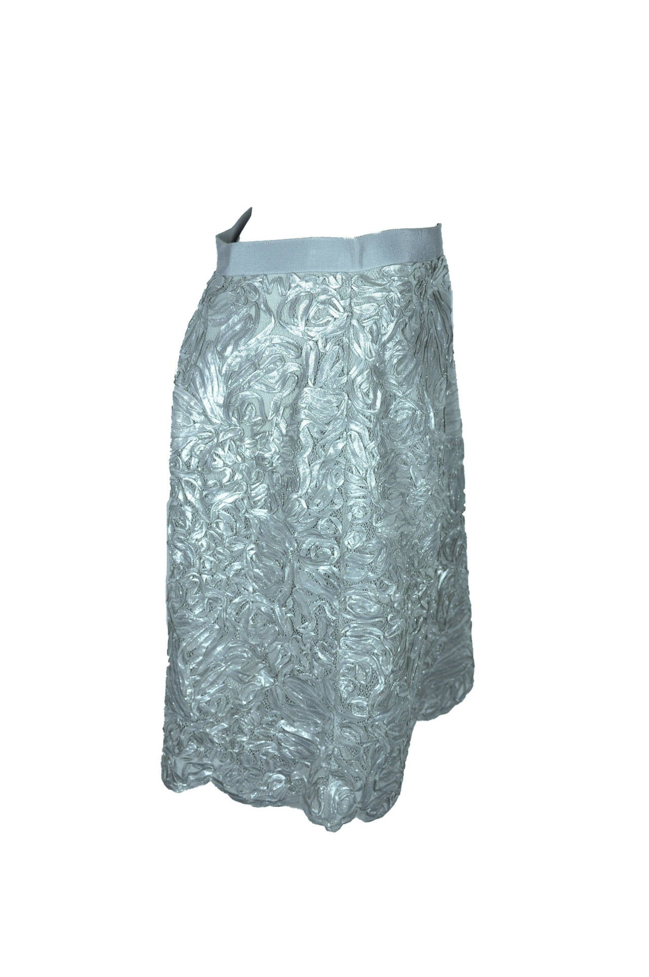 This elegant and feminine mini skirt is in a A-line shape with larger pleats at front. Fully crafted with silver embroidered applique ribbons on mesh.  Grosgrain banded waist, concealed zip fastening at side.  Fully lined.