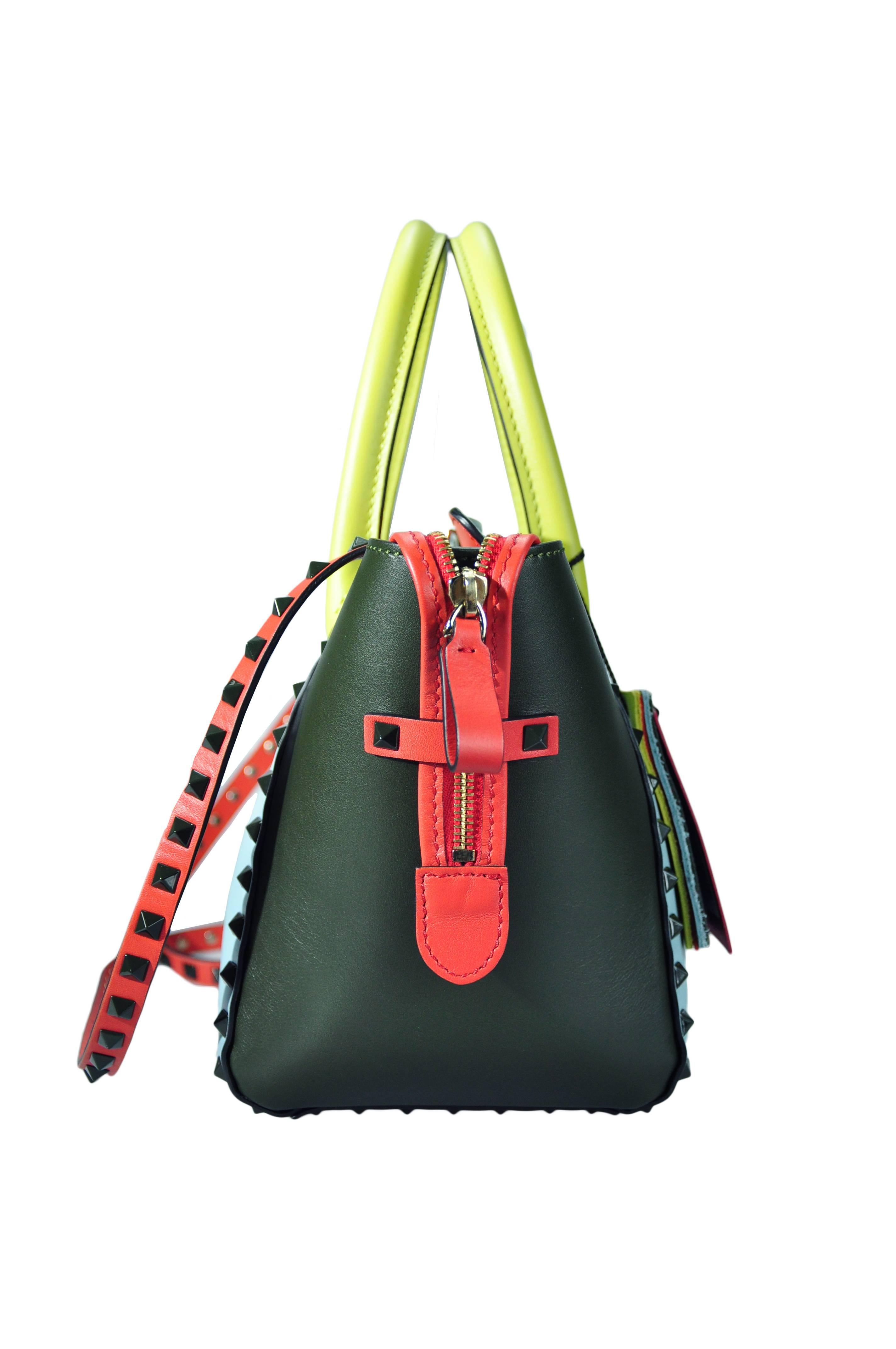 A Valentino Garavani Rockstud small trapeze tote bag in multi-colored calfskin, sky-blue, charcoal grey, red and yellow. Deep army lacquered studs with metal flip lock closure and zip fastening closure. Detachable studded strap, nappa lining, one