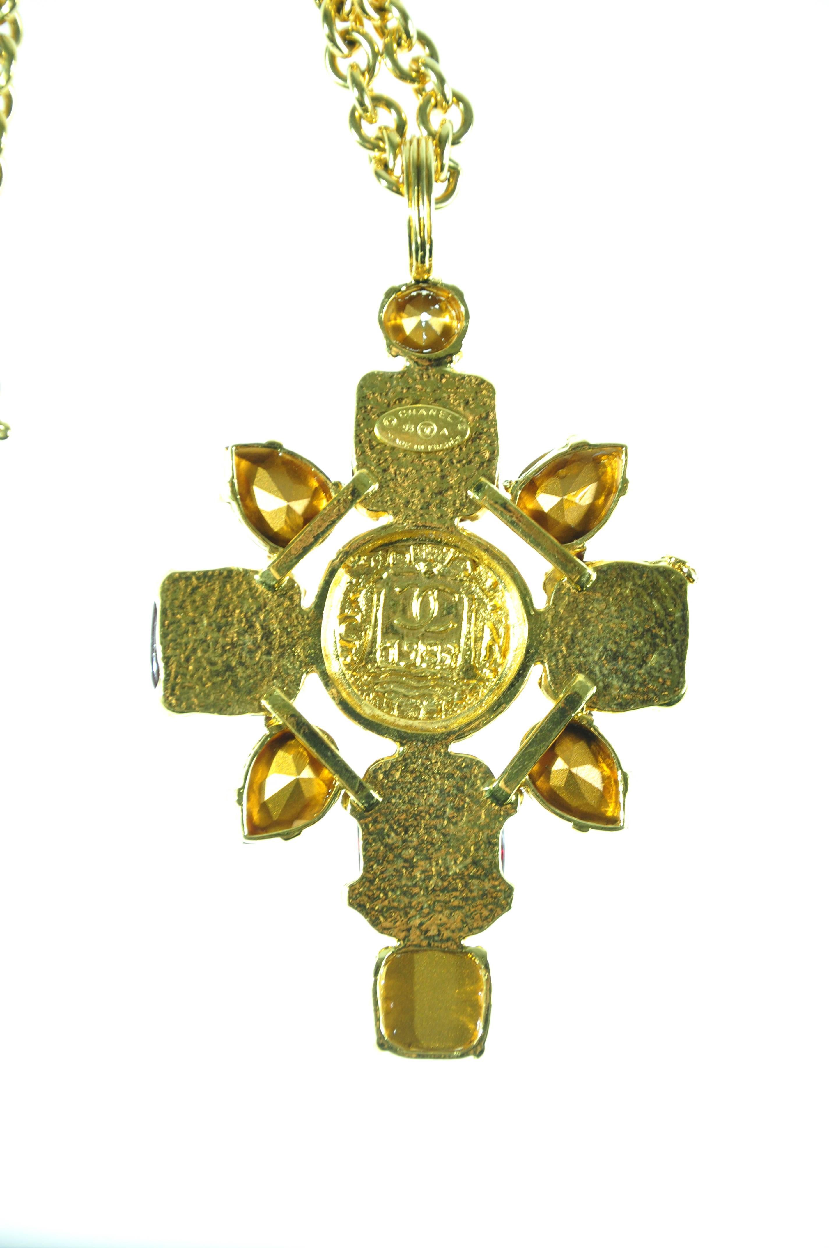 A collectible Chanel gold chain necklace with a large cross pendant in gilt metal centered by a chiseled coin circled with 4 large red gripoix and various shapes of crystals. The gilt metal stamped with Chanel, CC logo.  Clasp closure.
Pendant