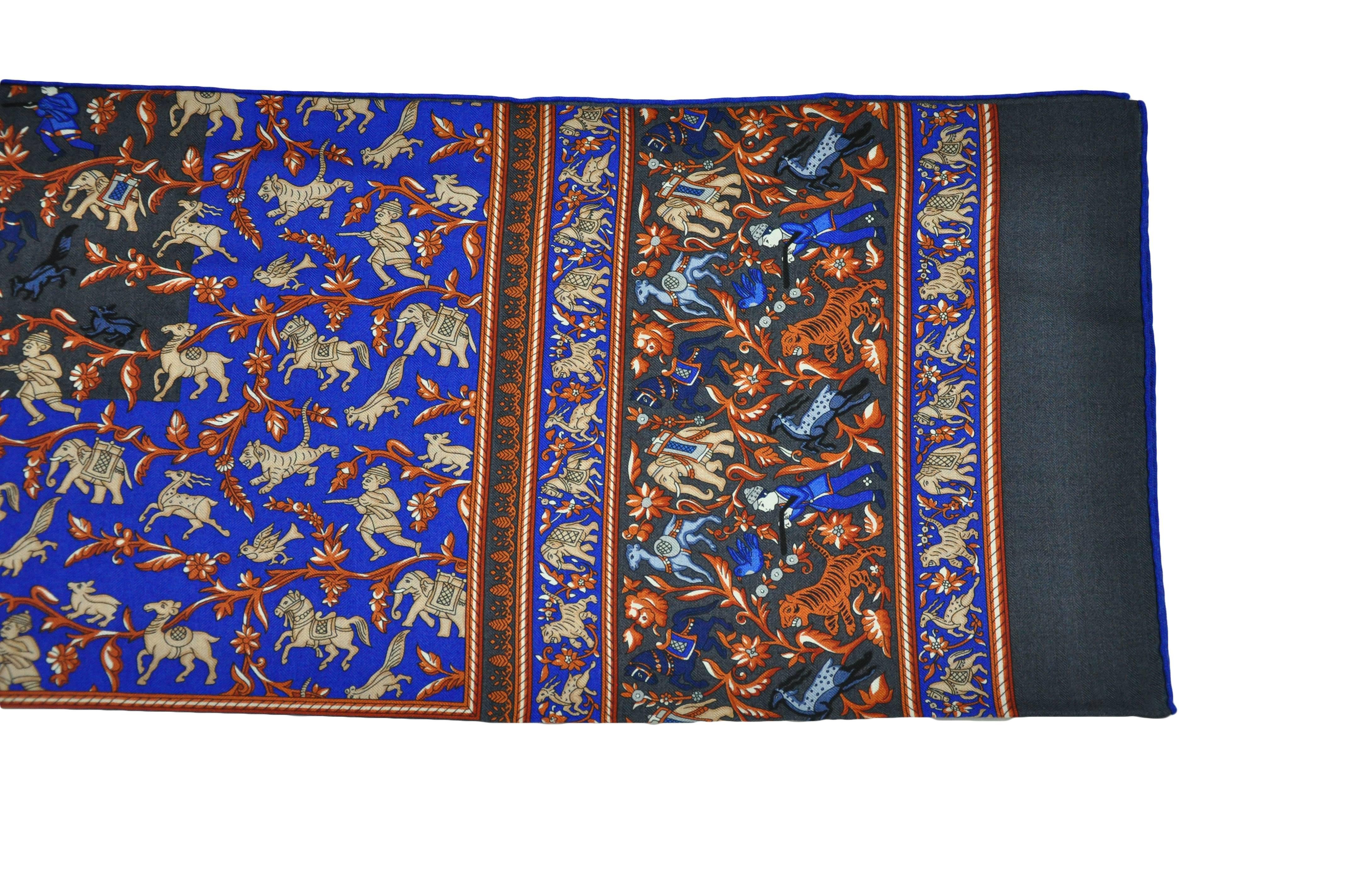 This Hermes 140 cm x 140 cm cashmere & silk shawl is beautifully printed with multiple animals and hunters from 2016 collection. A colorful combination in grey/electric blue/brown  Brand new in a Hermes gift box.