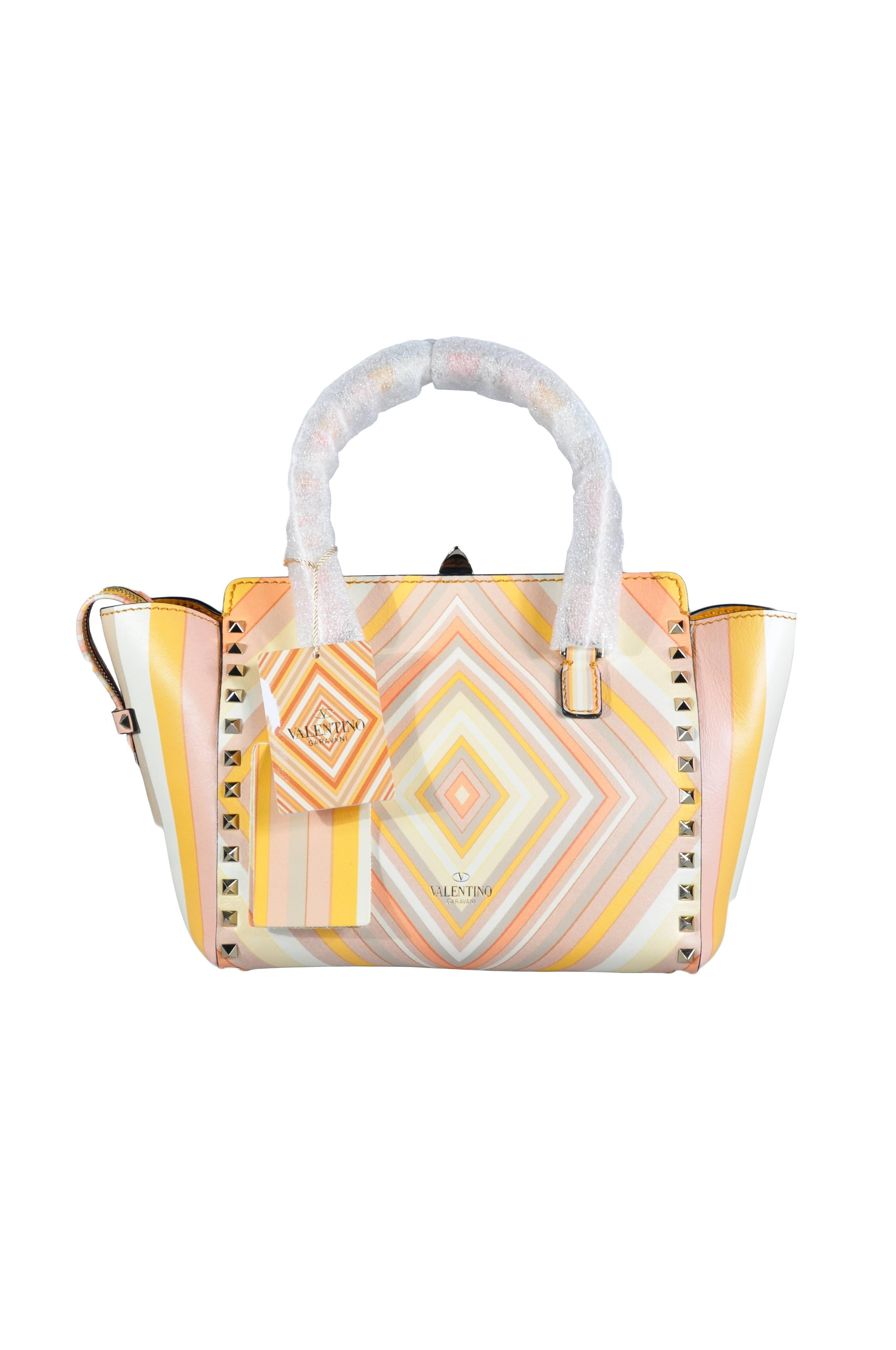 An iconic Valentino trapeze bag from their 2016 collection.  It features with their striking vintage native print with multiple colors.  Signature rockstuds trim body and strap, rolled top handles with detachable strap.  Recessed, zip-top with