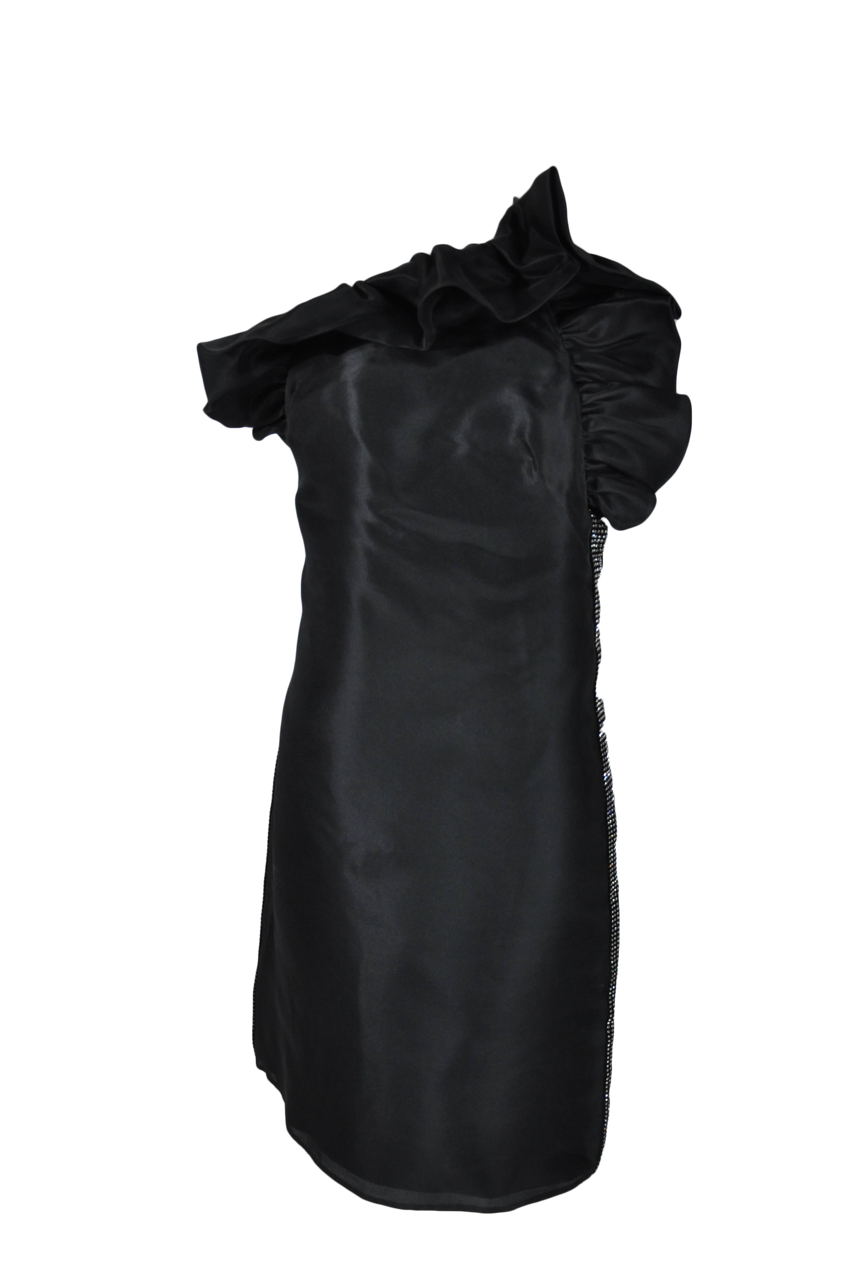 This ruffled neckline low back mini dress is made of organza with a leather strap across the back to hold the dress in shape. Beautifully adorned with crystals on sides.  Zip fastening at side. Fully lined.