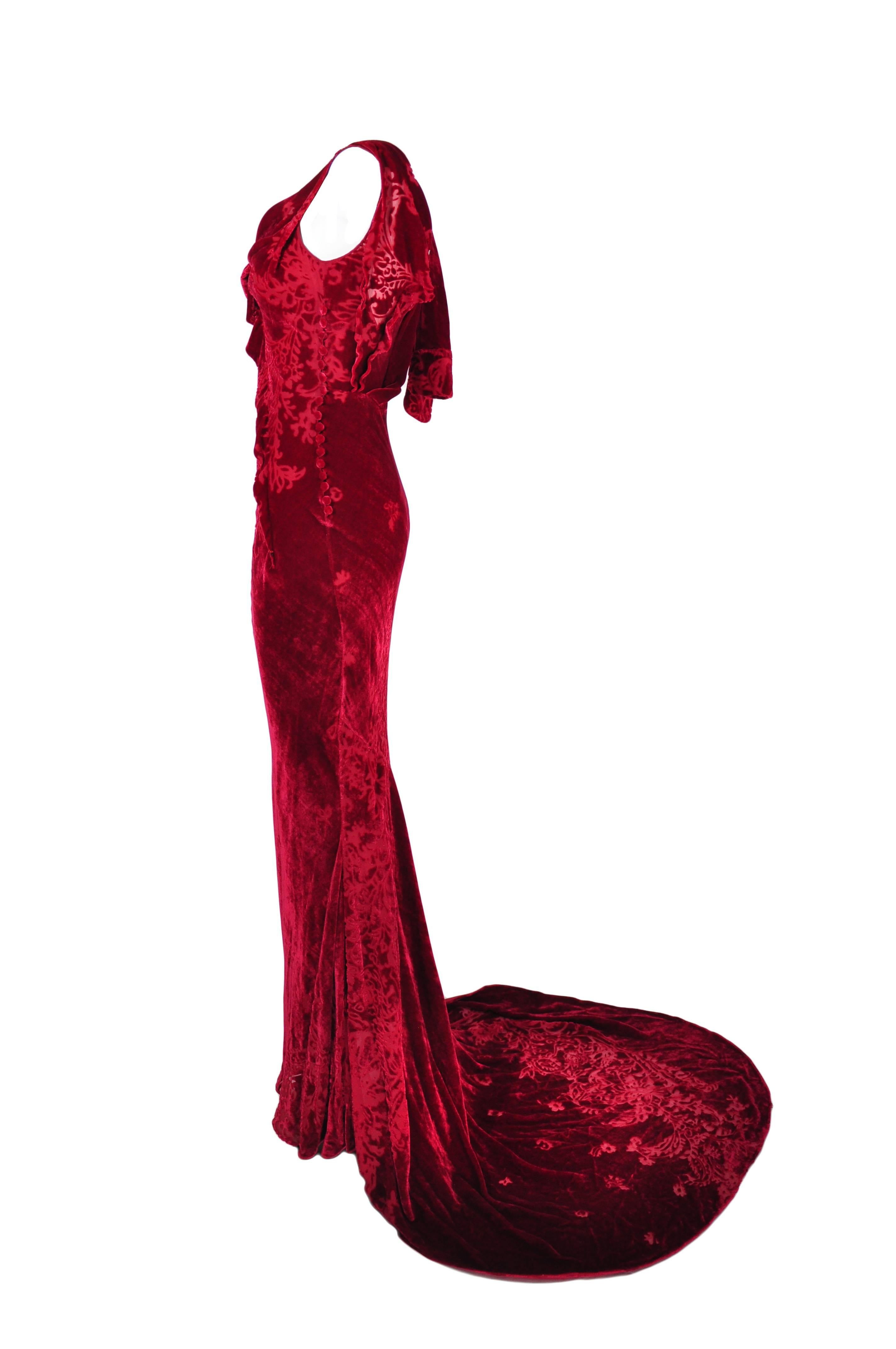 This draped evening gown definitely skims your silhouette with John Galliano's signature bias-cut. Multiple button fastenings at side with a long sweeping train.
Lined in silk.