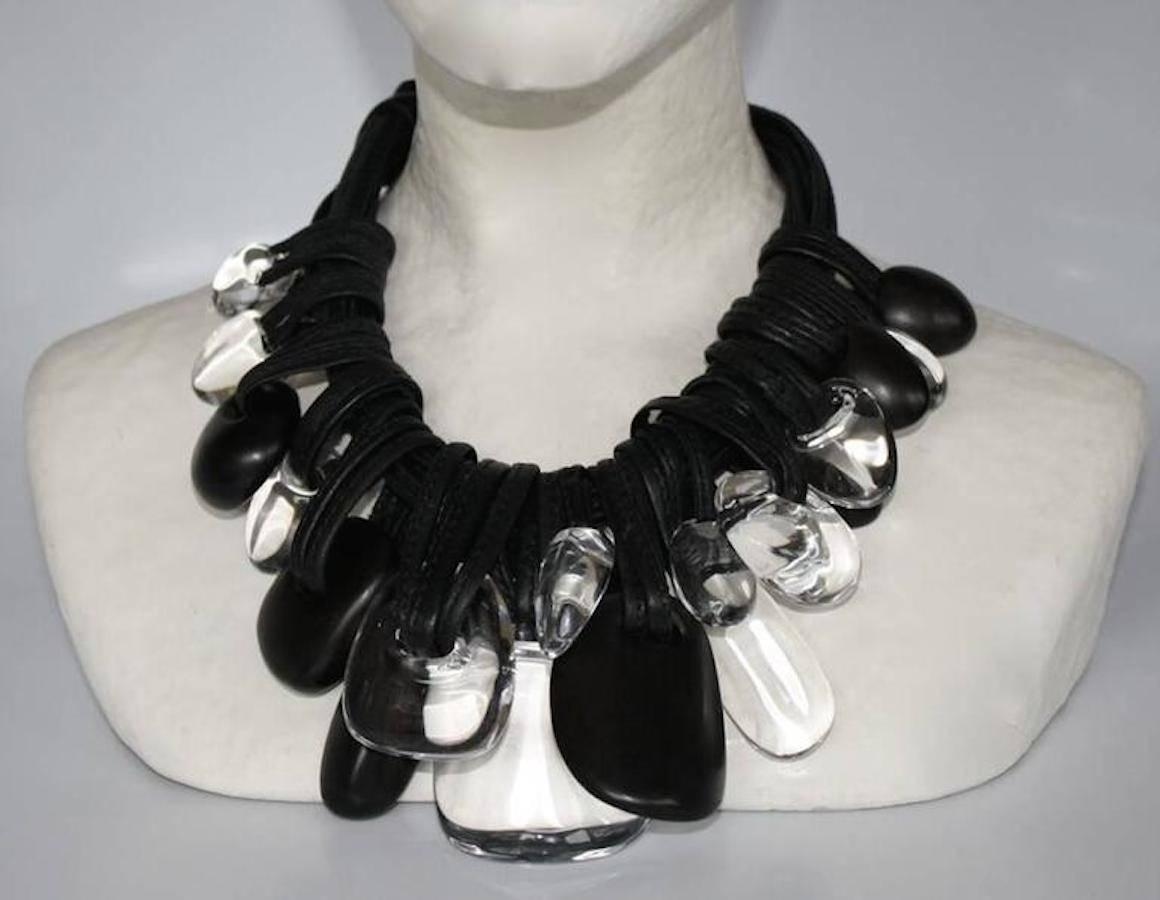 Lightweight statement necklace made with multiple strands of leather, ebony wood, and clear acrylic drops from Monies.   

Designer Biography:  

Monies is a Danish jewelry company founded by Gerda and Nikolai Monies. We are trained goldsmiths with